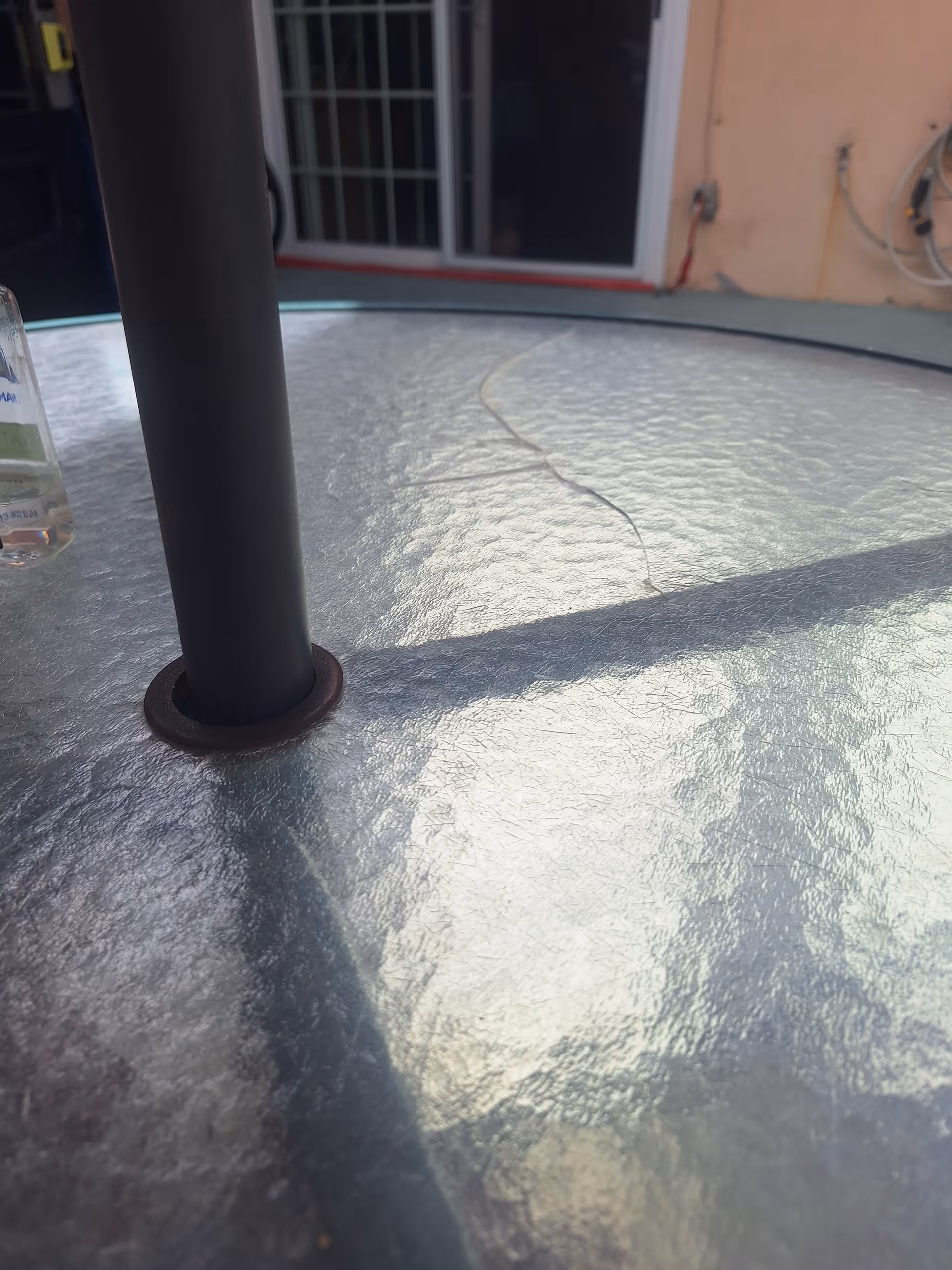 Outdoor table with a black pole on a textured metal surface, building exterior in background.