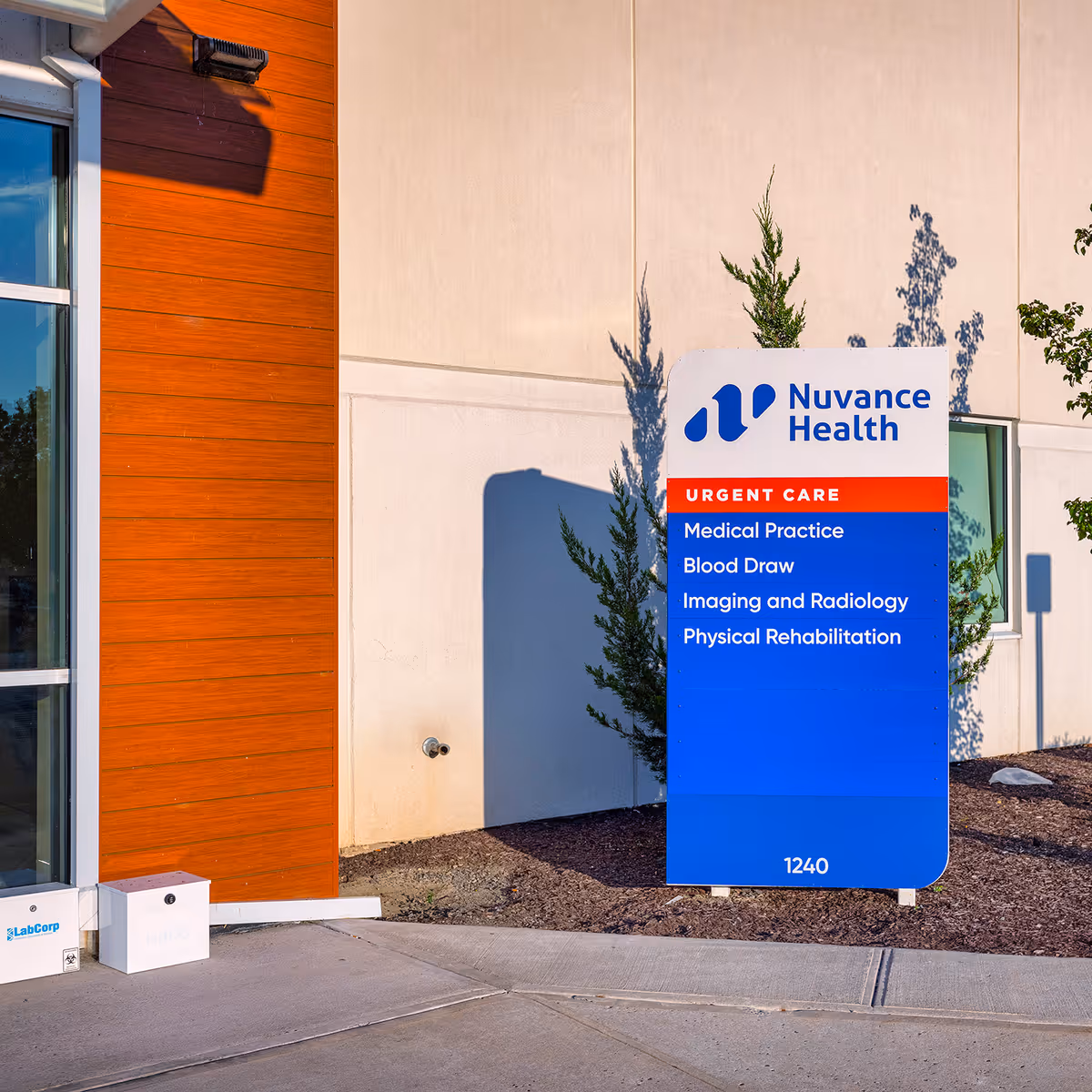Exterior of a medical building with blue Nuvance Health sign and urgent care panel.