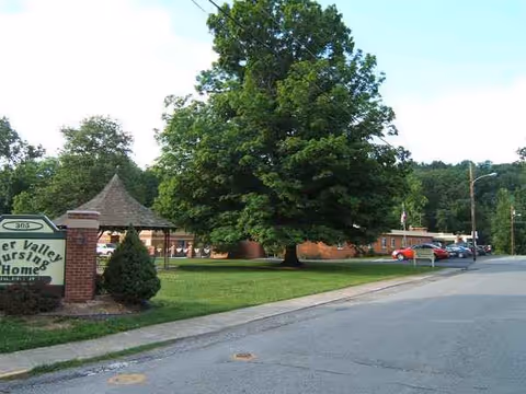 Exterior view of River Valley Nursing Home with a large tree and sign.