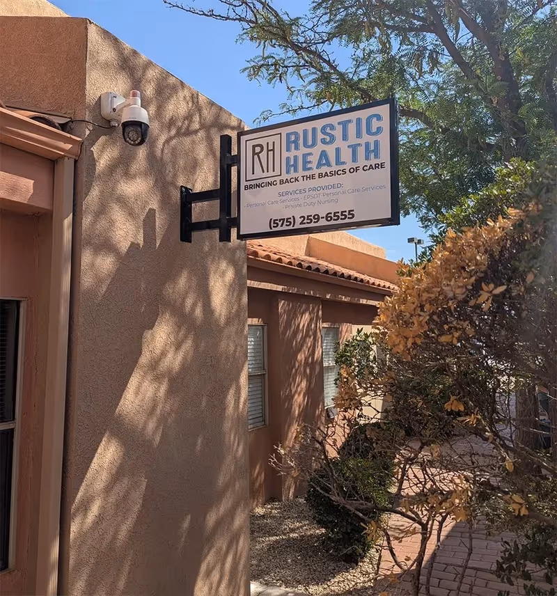 Exterior view of Rustic Health LLC sign on a stucco building entrance.