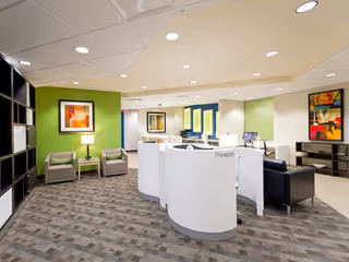 Curved white reception desk with seating area in a modern senior living facility lobby.