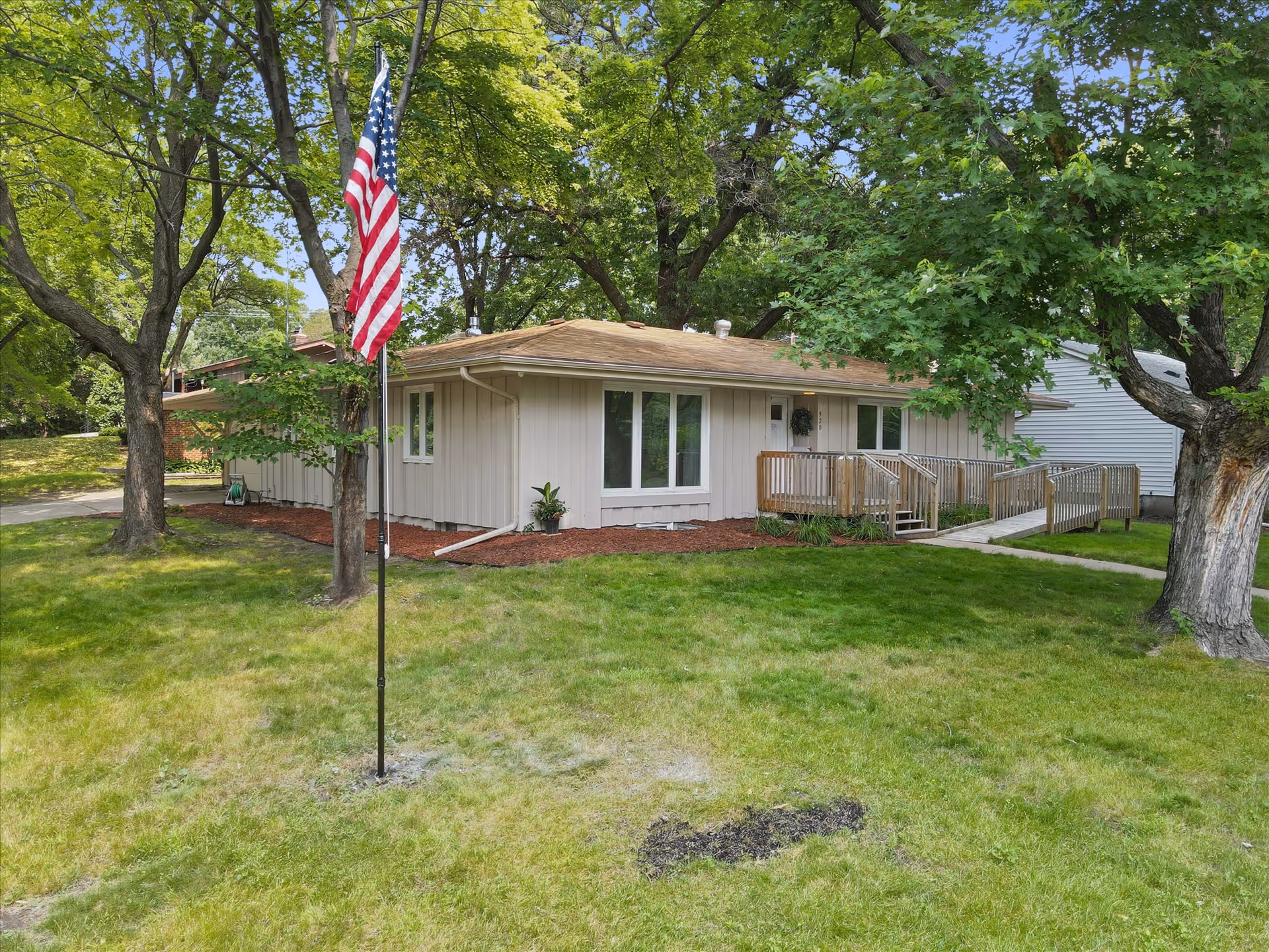 Single-story beige building with ramp access, flagpole, and a landscaped front lawn.