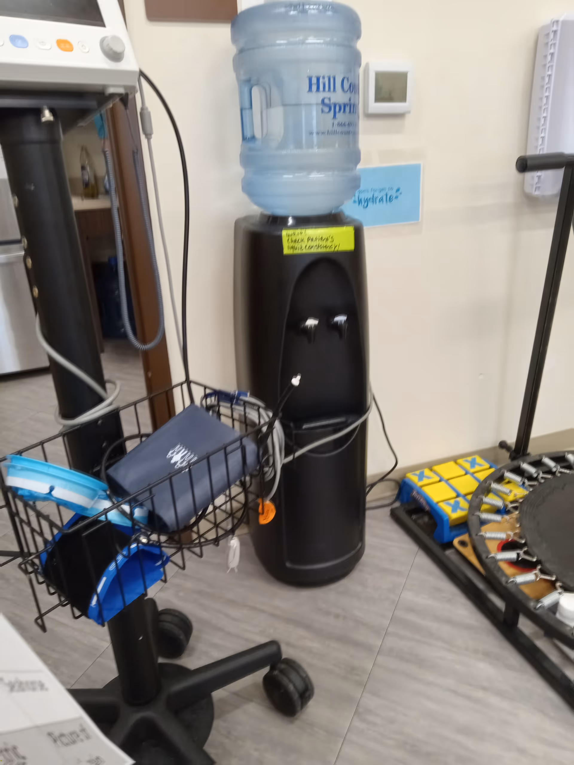 Interior facility scene with a water cooler, equipment cart, and exercise setup.
