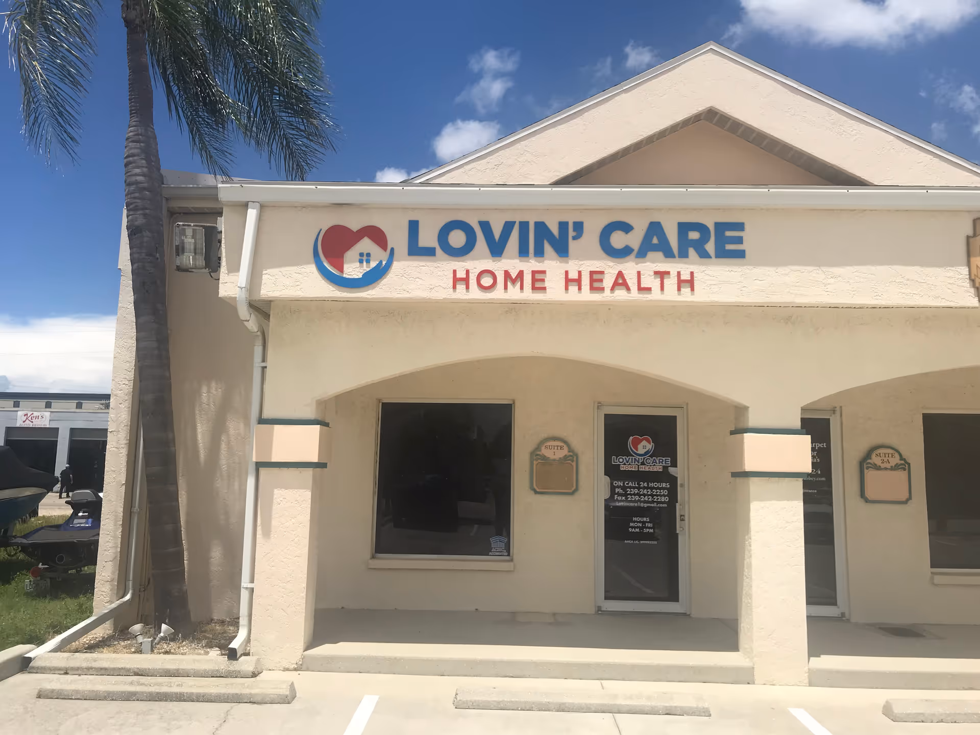 Exterior of Lovin' Care Home Health building with sign, palm tree, and blue sky.