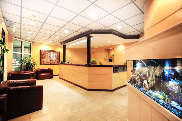 A spacious senior living facility lobby with a curved reception desk, seating, and an aquarium.