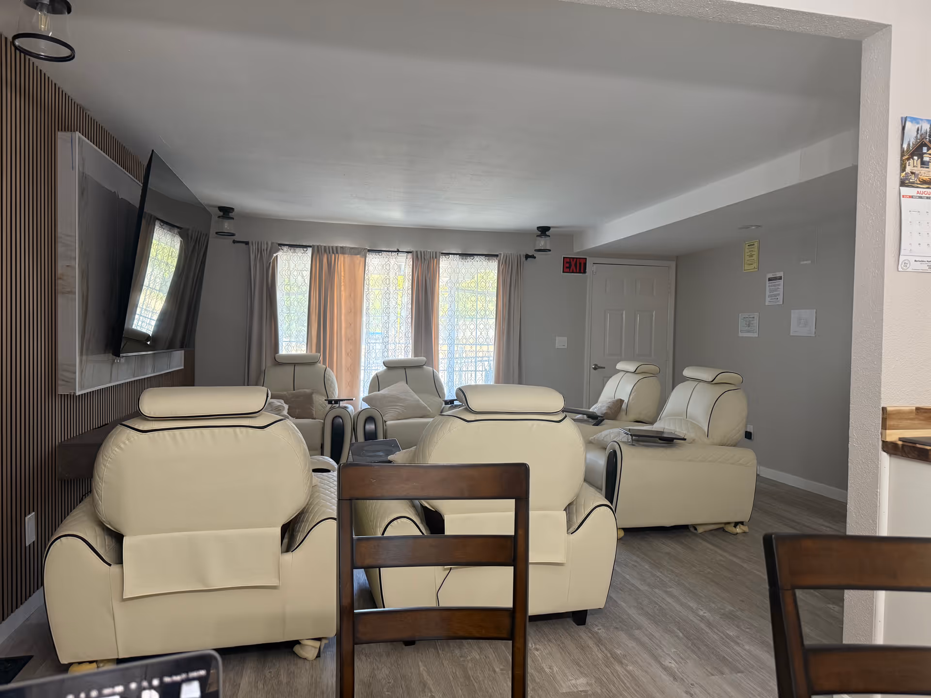 Cream-colored recliner chairs arranged in a living room with a wall-mounted TV.