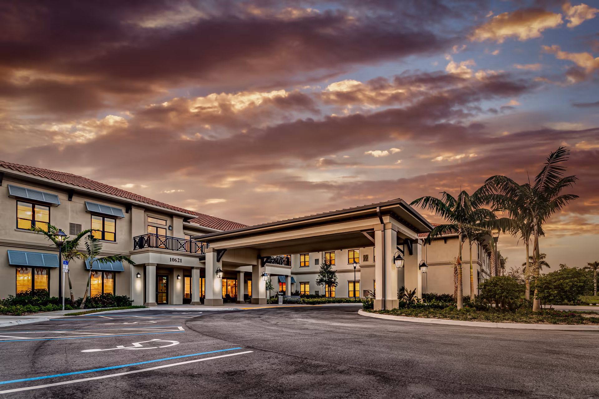 Exterior view of The Capstone at Royal Palm Senior Living with entrance, parking, and palms