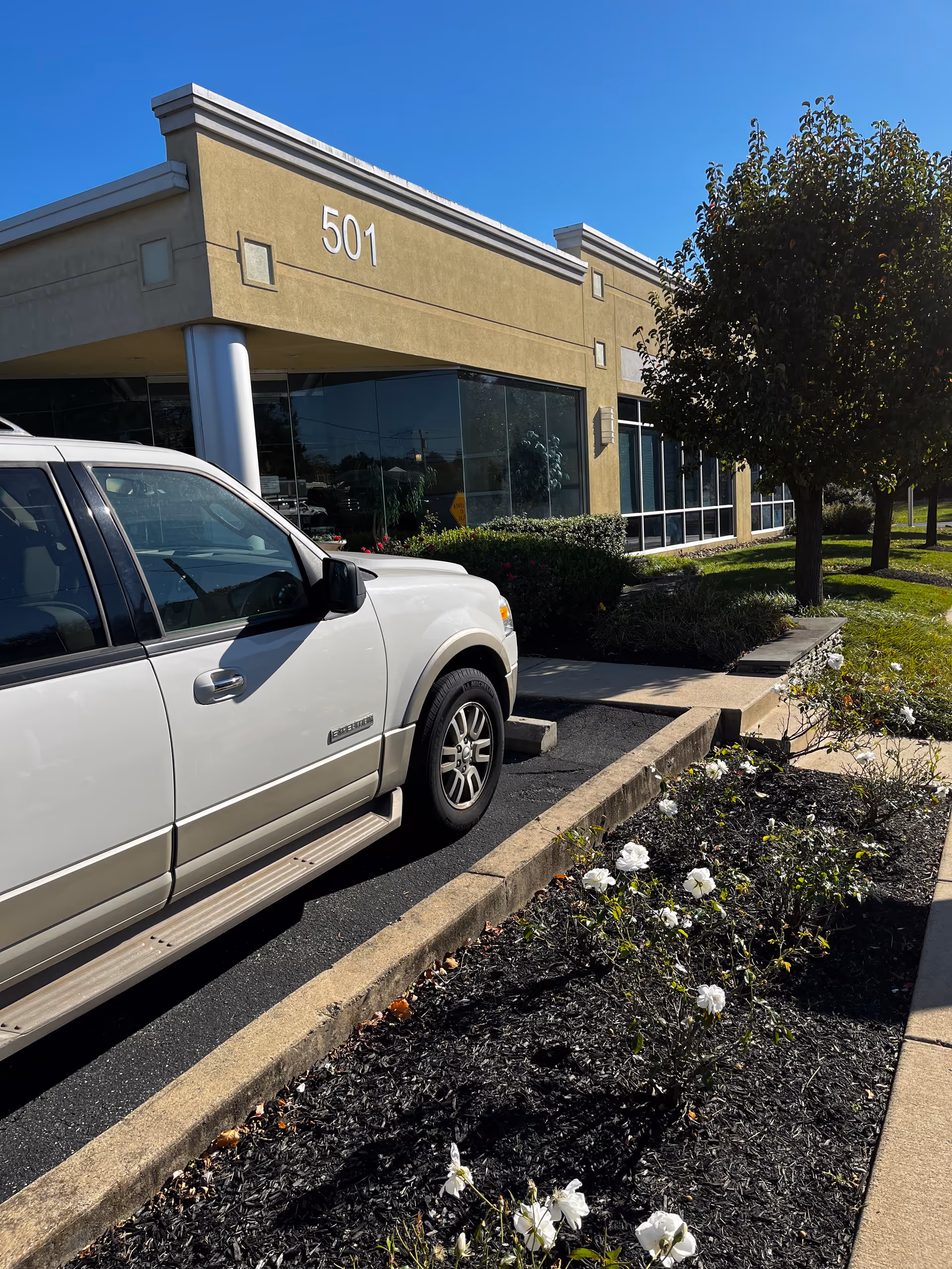 White SUV parked beside a tan building labeled 501 with landscaping.