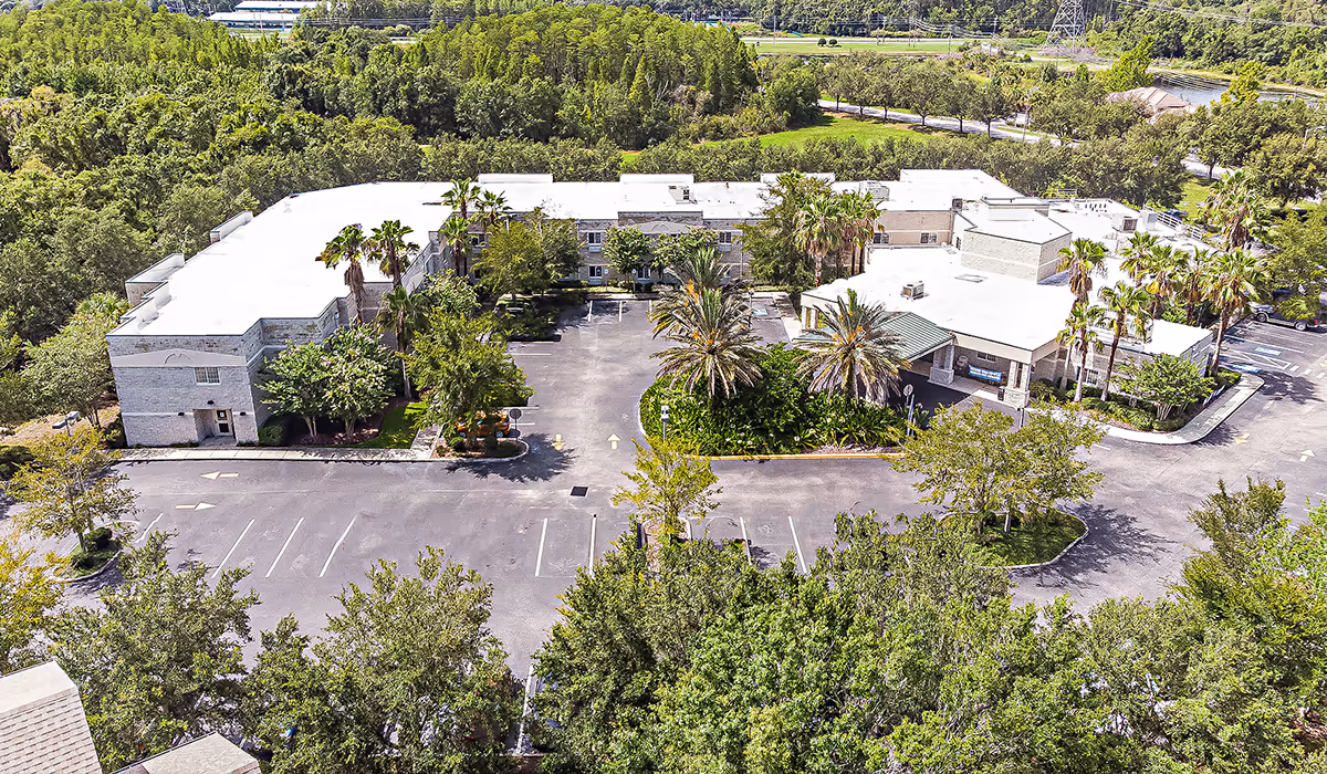 Aerial view of a single-story senior living campus with parking and surrounding trees.