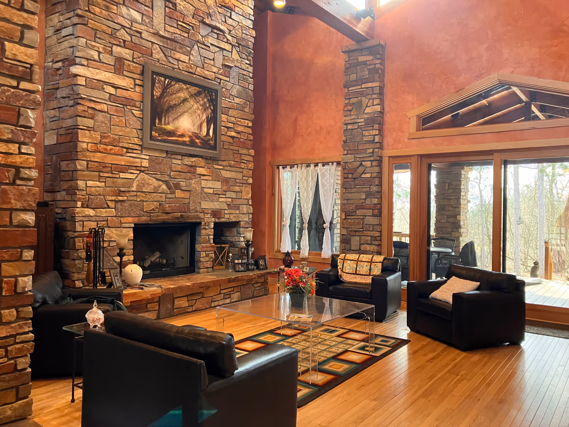 Cozy stone fireplace with seating area and large windows in living room.