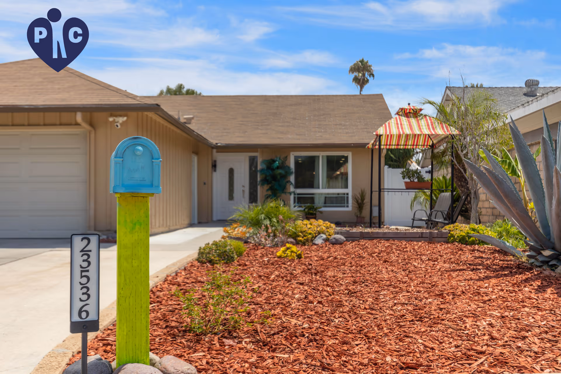 Front yard and entrance of a single-story senior living facility with mulch and outdoor seating.