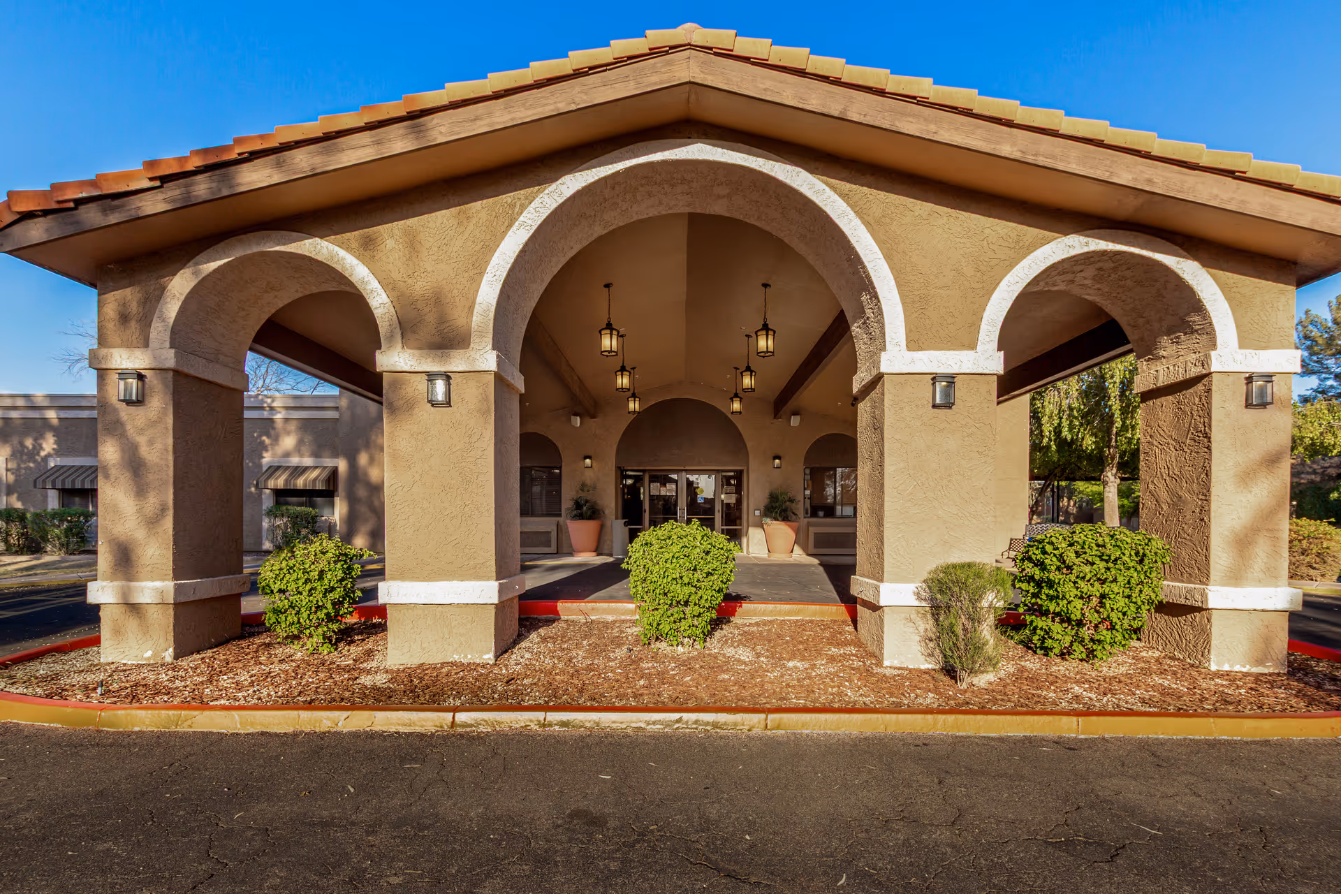Front view of Springdale Village, a beige senior living facility with arched entrance and landscaping.
