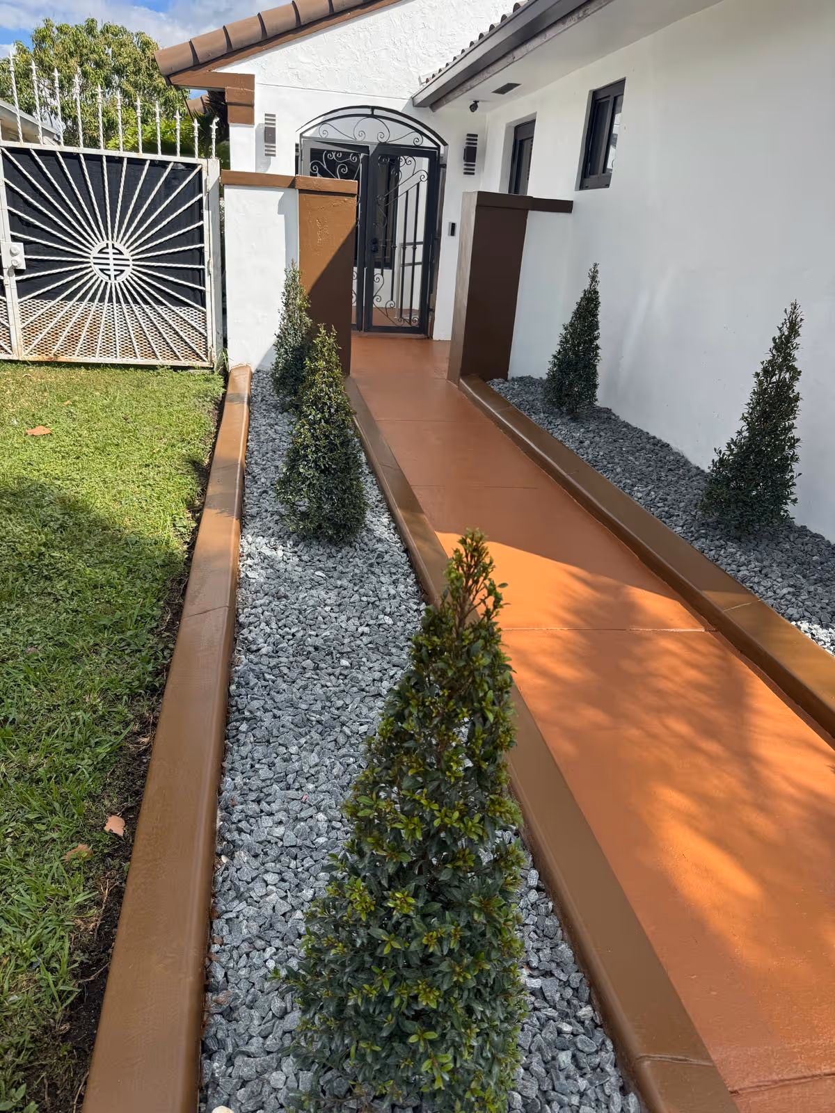 Gated entrance to Cruz Family ALF No 2 with a landscaped gravel path.