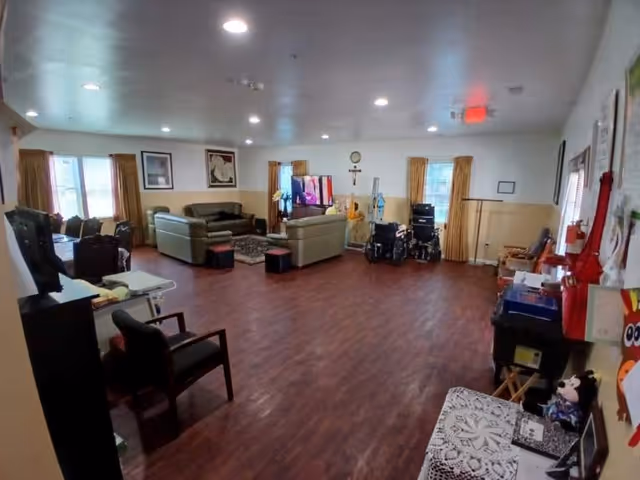 Spacious common living room in a retirement facility with sofas, chairs, and a TV.