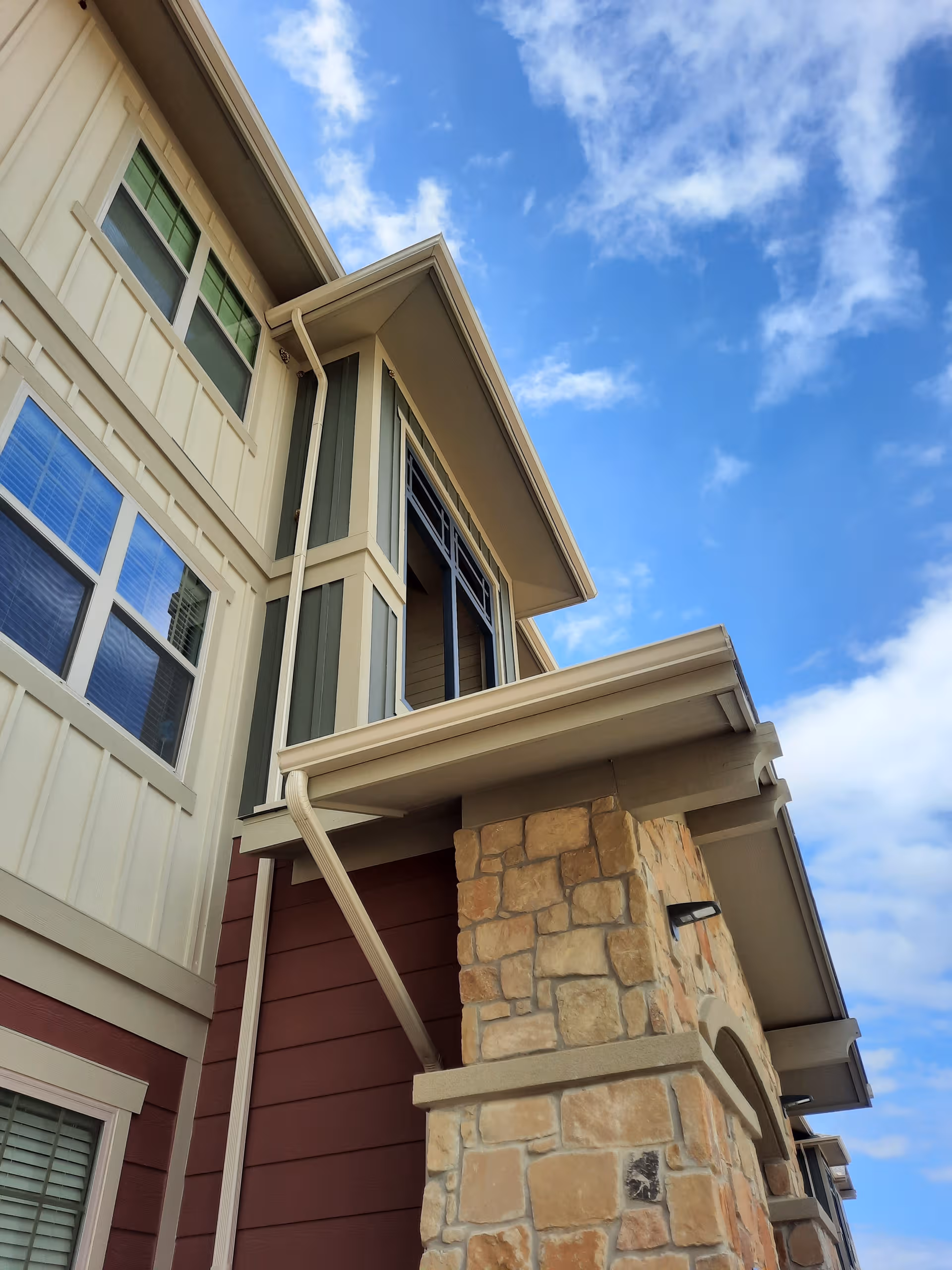 Exterior view of a two-story senior living building with stone pillar and blue sky.