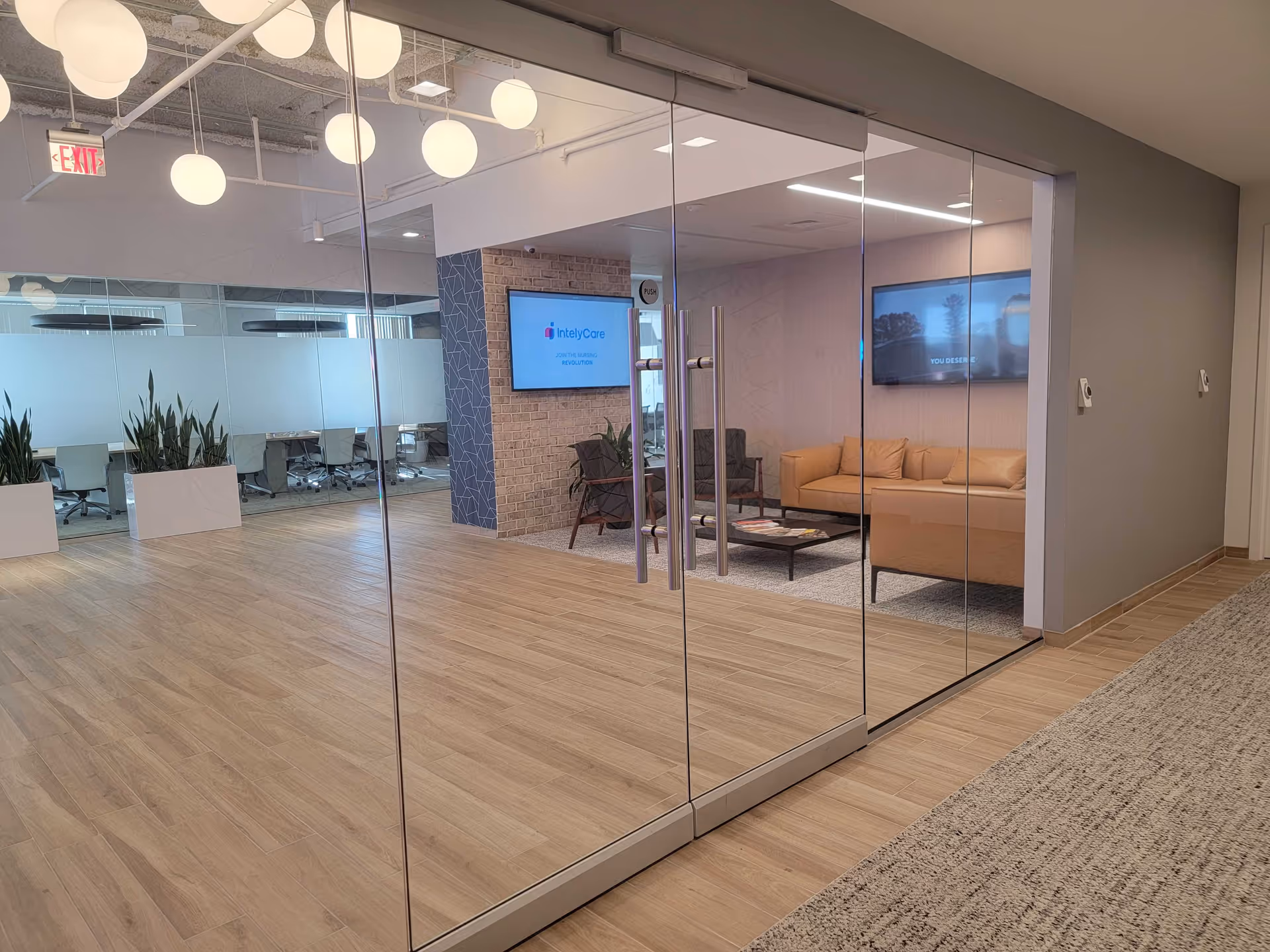 Glass-walled lobby with seating area, plants, and conference room visible.