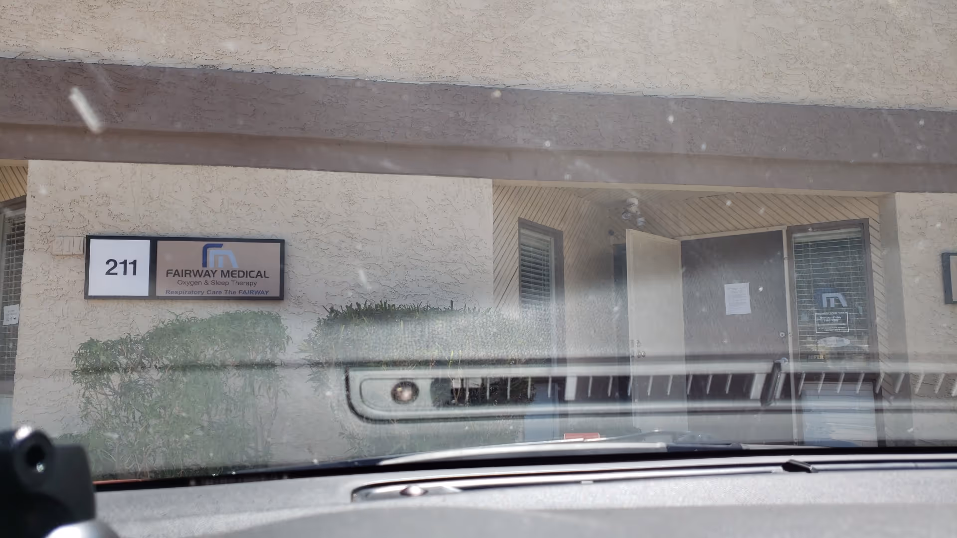 Exterior view of Fairway Medical front entrance with sign; reflection on car windshield.