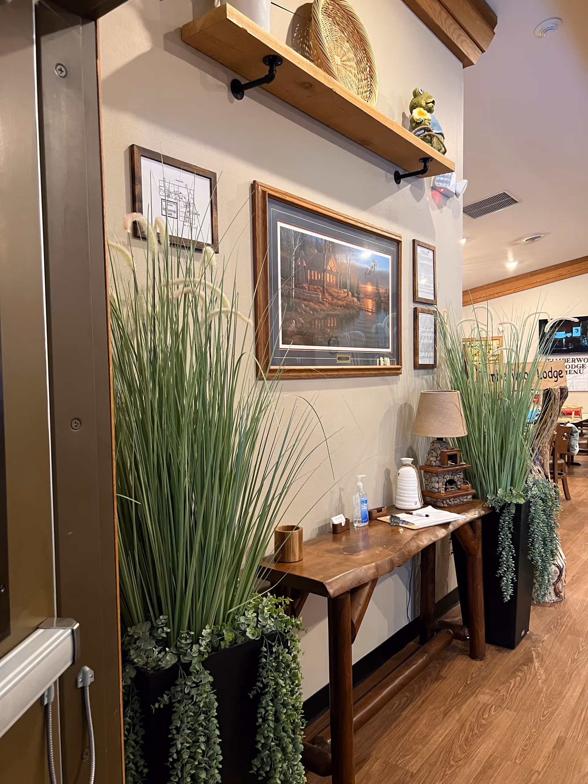 Interior hallway with a wooden console table, tall potted plants, and framed art.