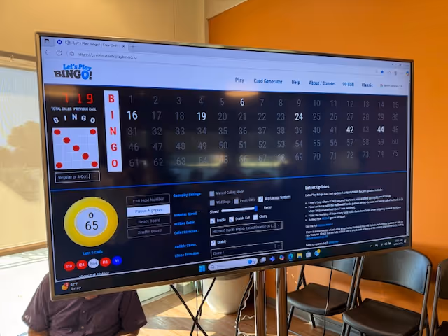 Large monitor shows bingo game interface with BINGO board, numbers, and a yellow caller circle.