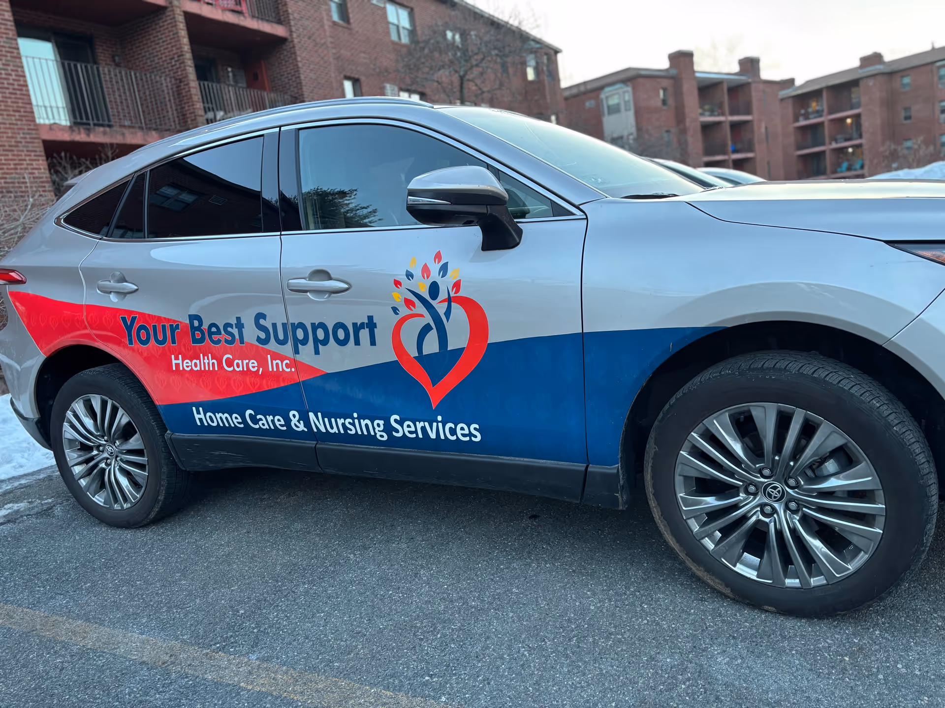 Branded service car for Your Best Support Health Care, Inc. parked outdoors near apartment buildings.