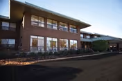 Exterior view of a two-story brick healthcare center with large windows.
