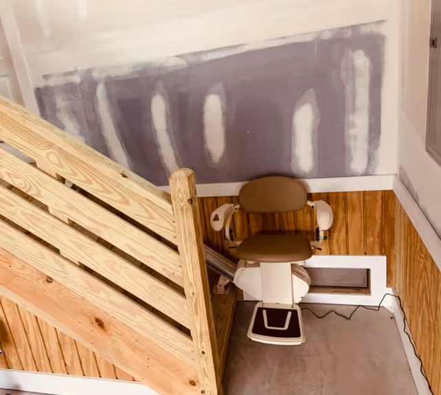 Interior view of a stairlift chair installed along a wooden staircase in a senior facility.