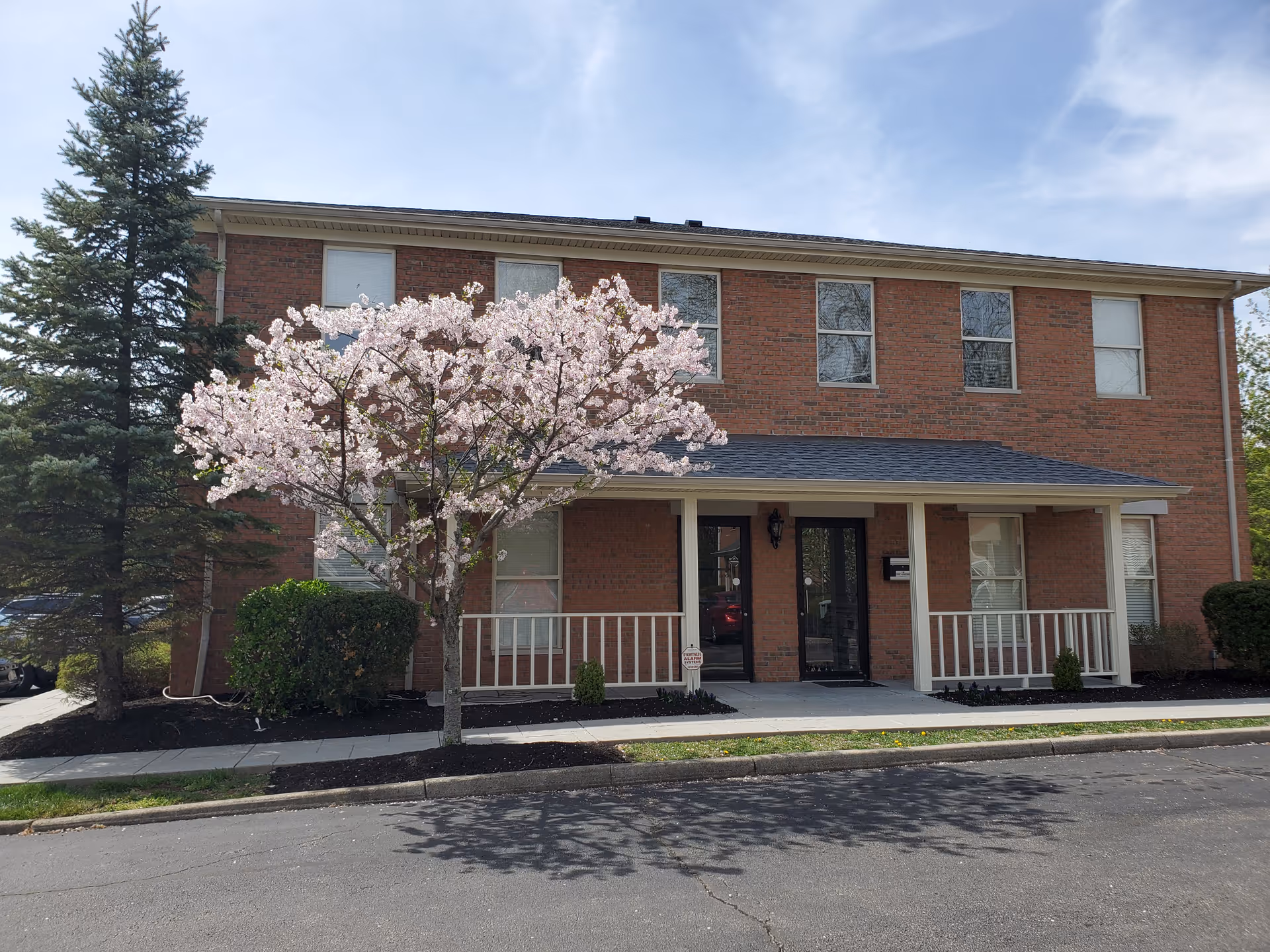 Brick two-story facility with a blooming tree near the front entrance
