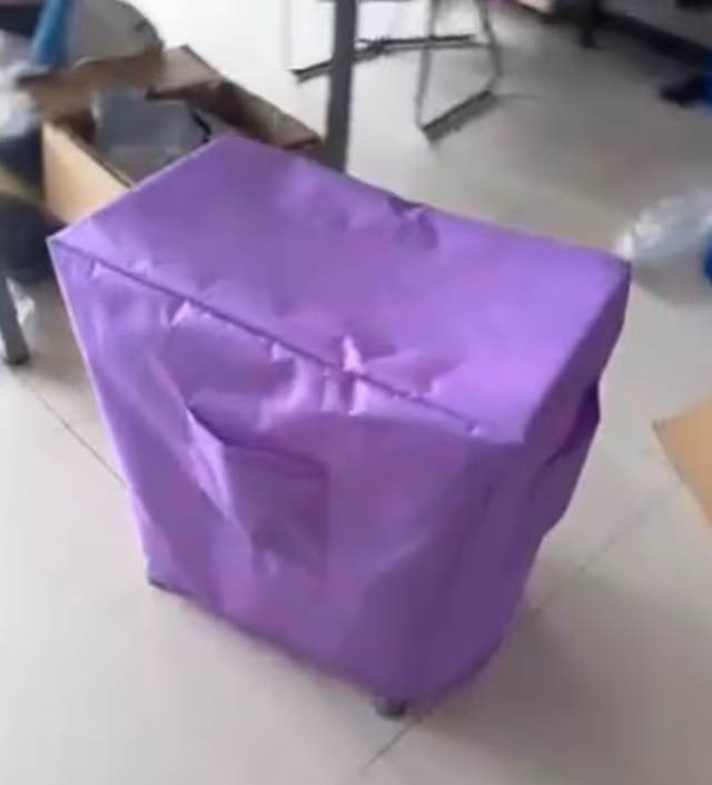 Purple-covered cube-shaped furniture item on a tiled indoor floor.