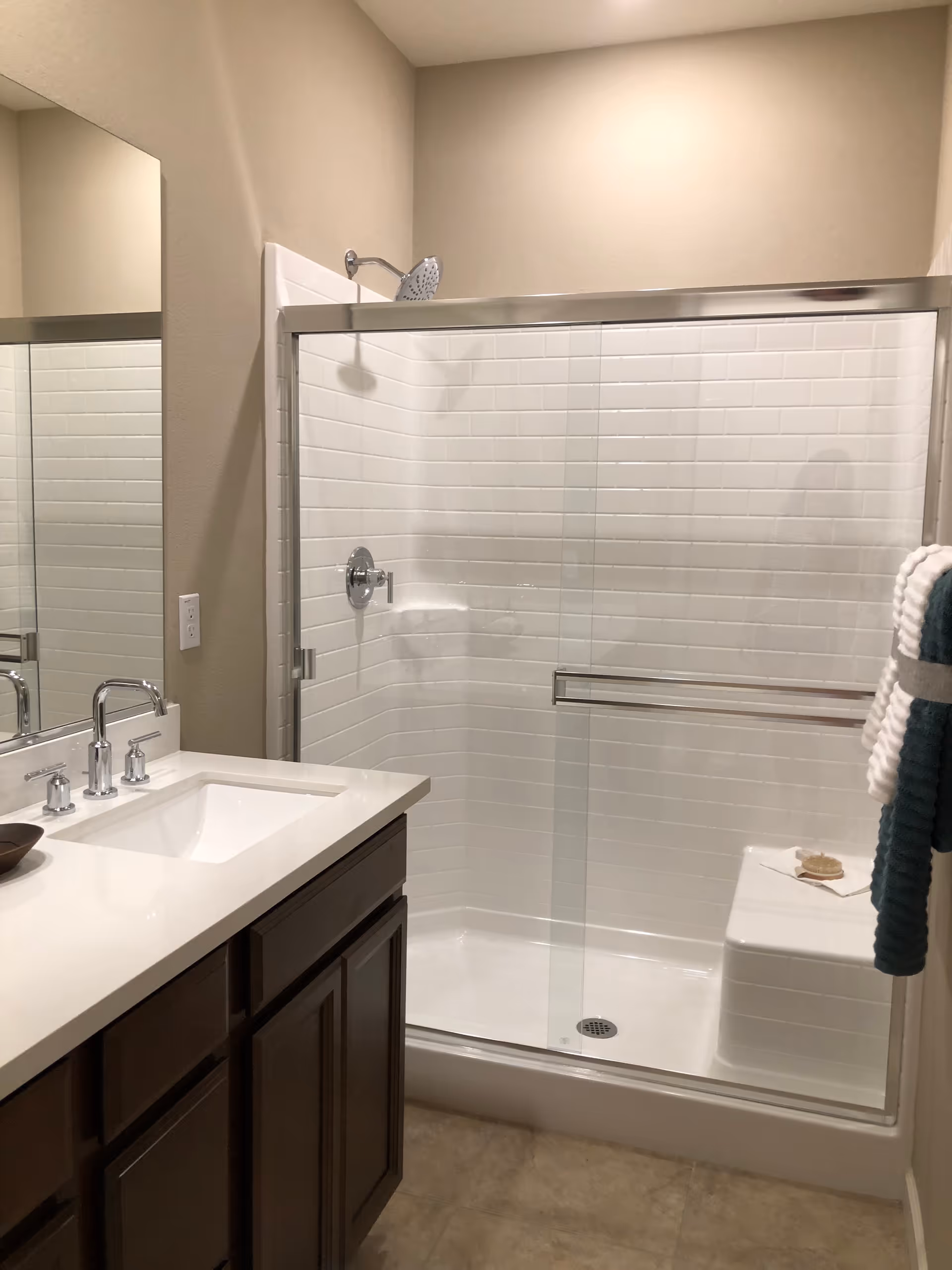 Bathroom inside a care home featuring a double-sink vanity and glass shower.