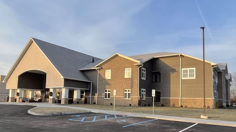 Modern two-story senior living facility with a covered entrance and parking lot.
