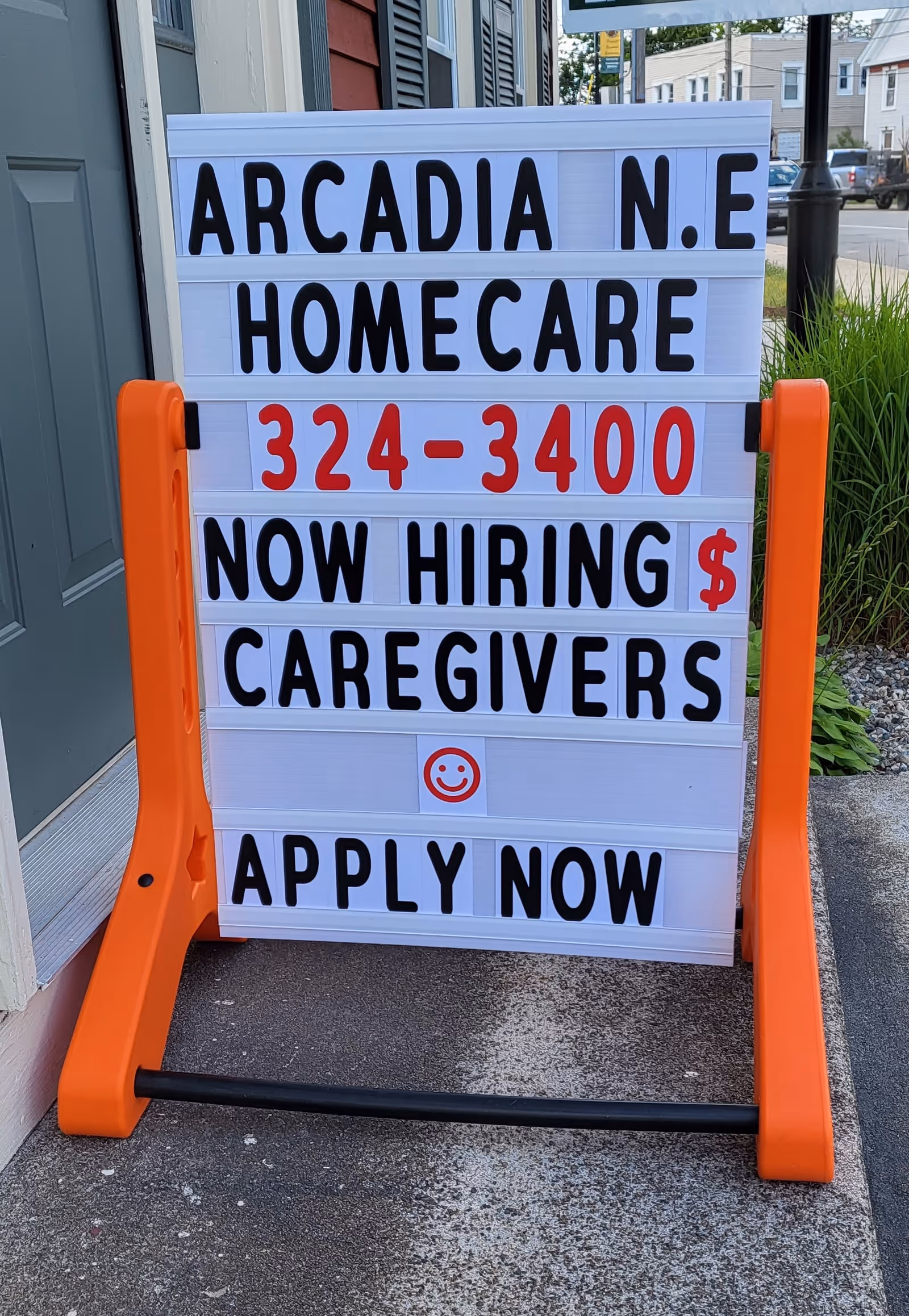Outdoor signboard advertising Arcadia N.E. HomeCare and now hiring caregivers outside entrance.