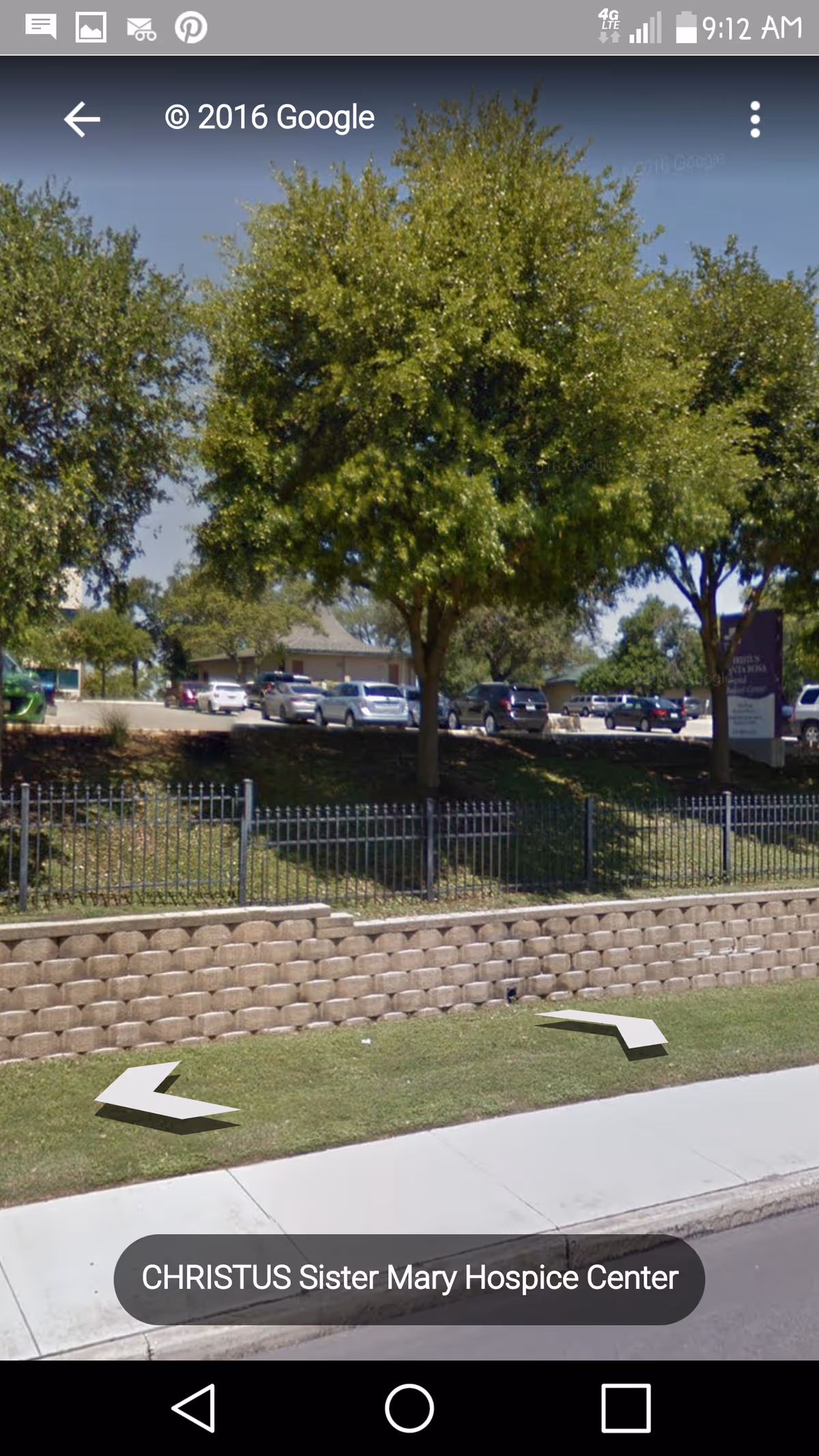 Exterior view of CHRISTUS Sister Mary Hospice Center with trees, fence, and parked cars.