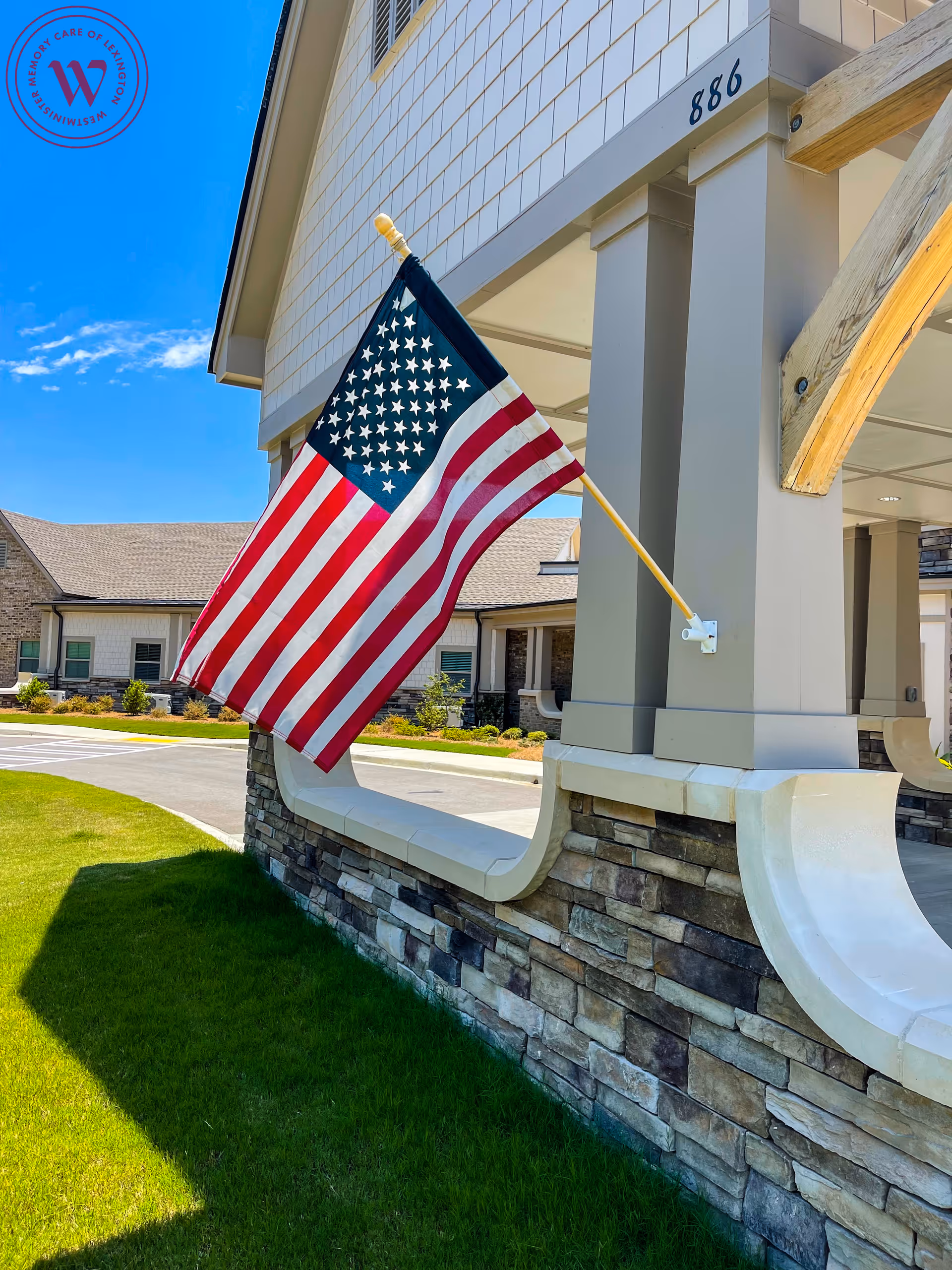 Westminster Memory Care exterior with a waving American flag on the entrance pillar.