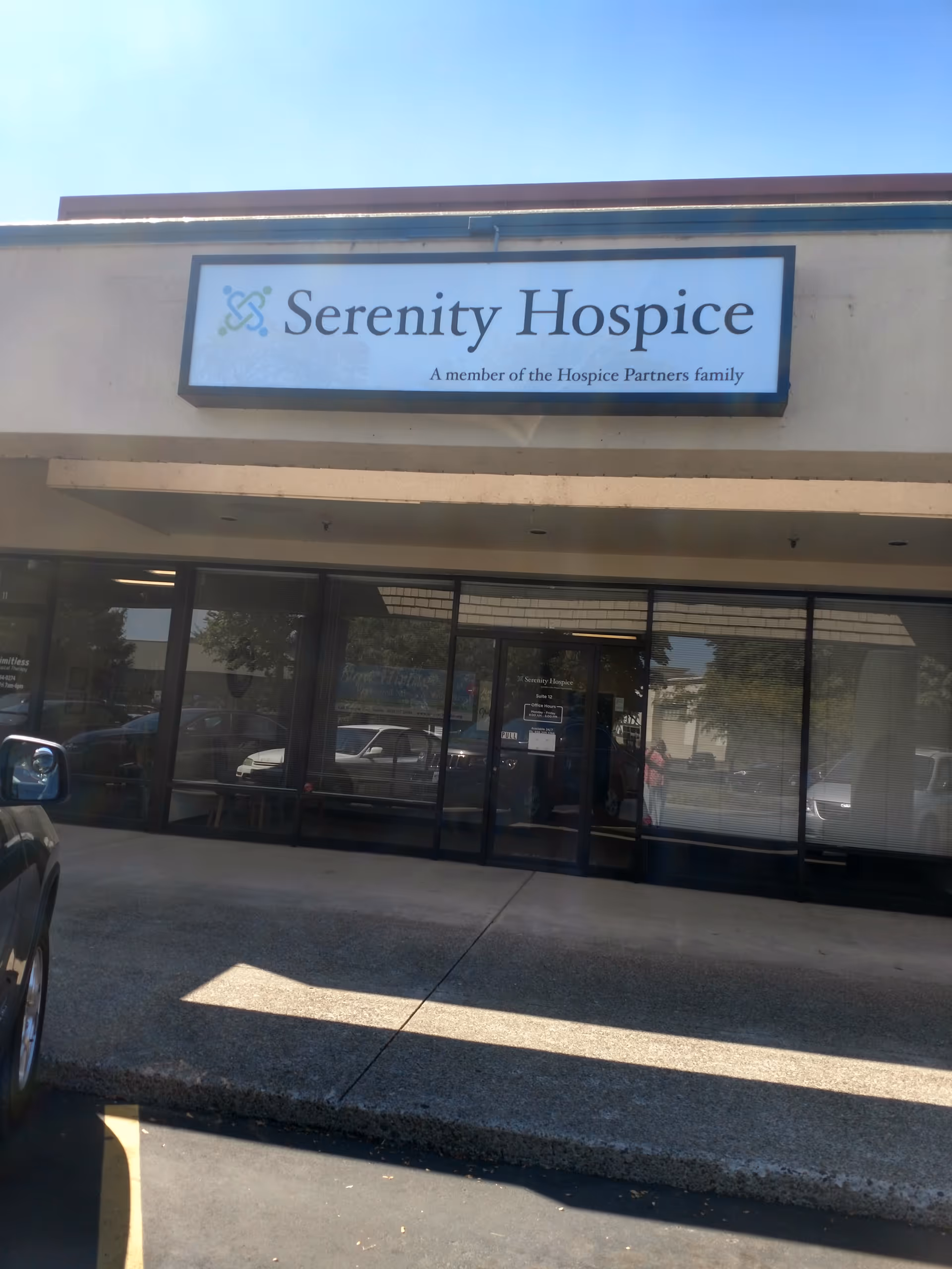 Front of Serenity Hospice facility with glass doors and a prominent sign above entry.