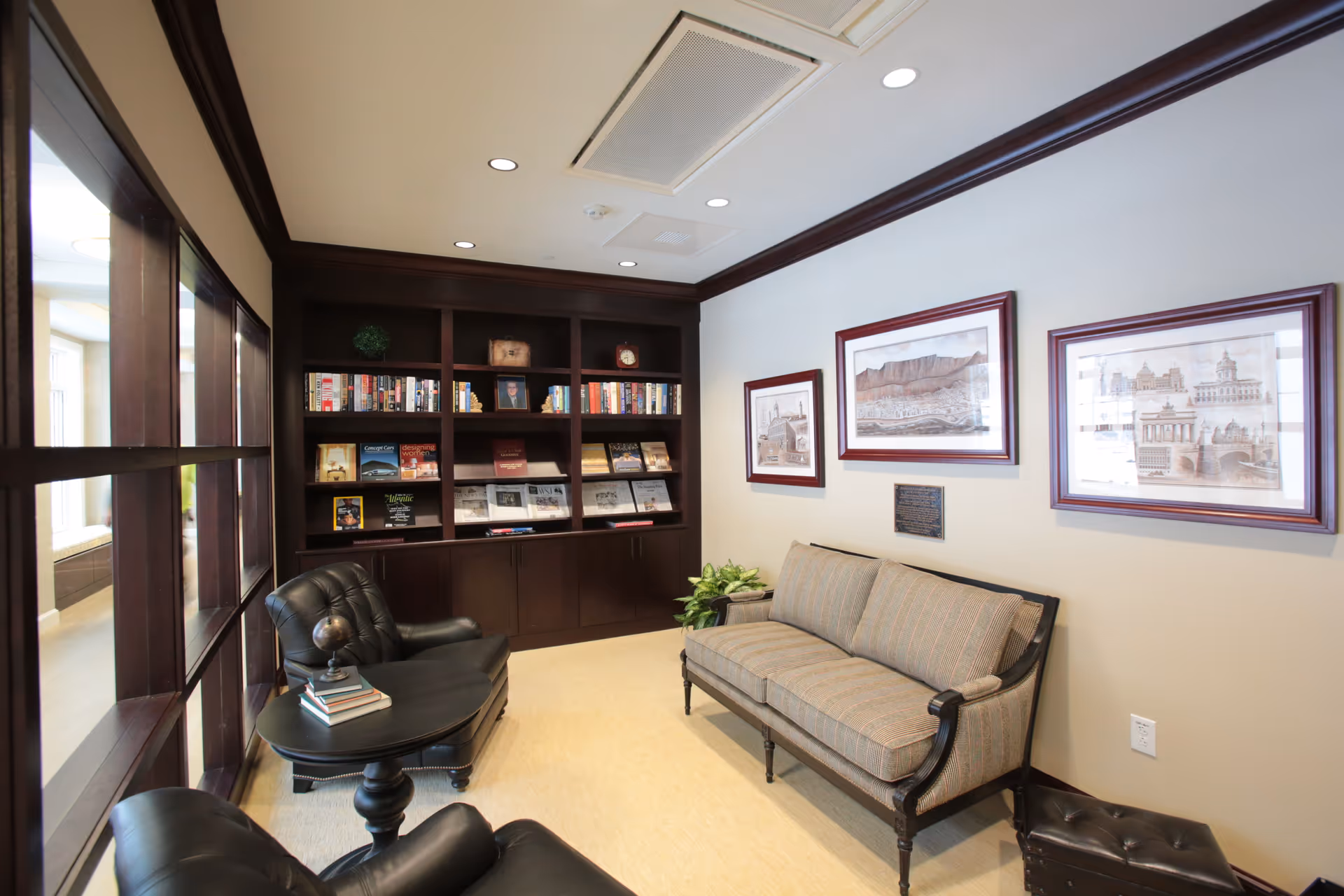 Cozy waiting area with dark wood bookshelves, framed art, and cushioned seating.