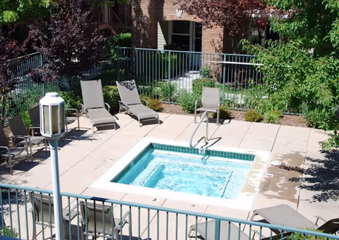 Outdoor pool surrounded by lounge chairs and greenery in a courtyard.