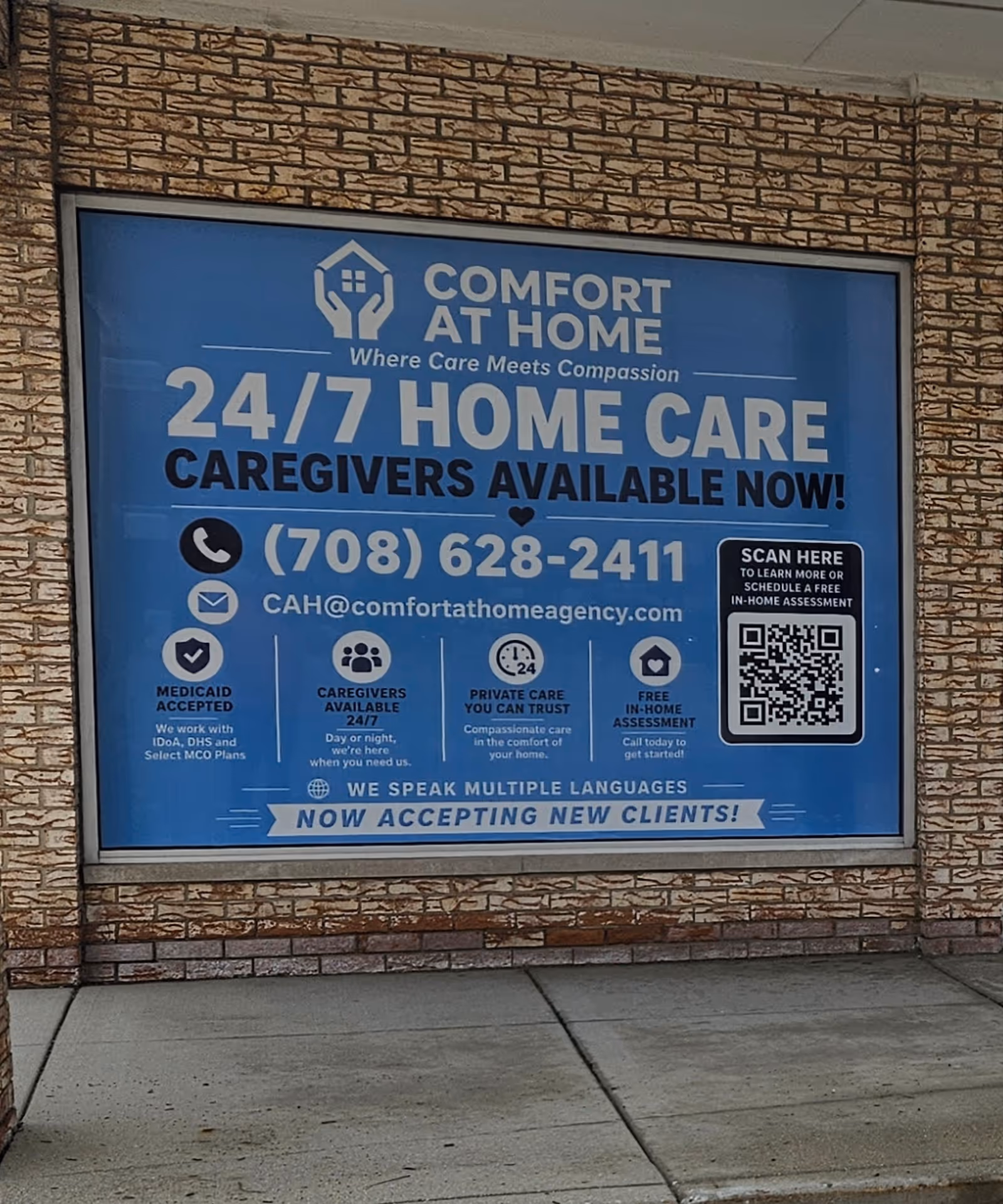 Large blue sign on brick exterior advertising Comfort At Home home care services.