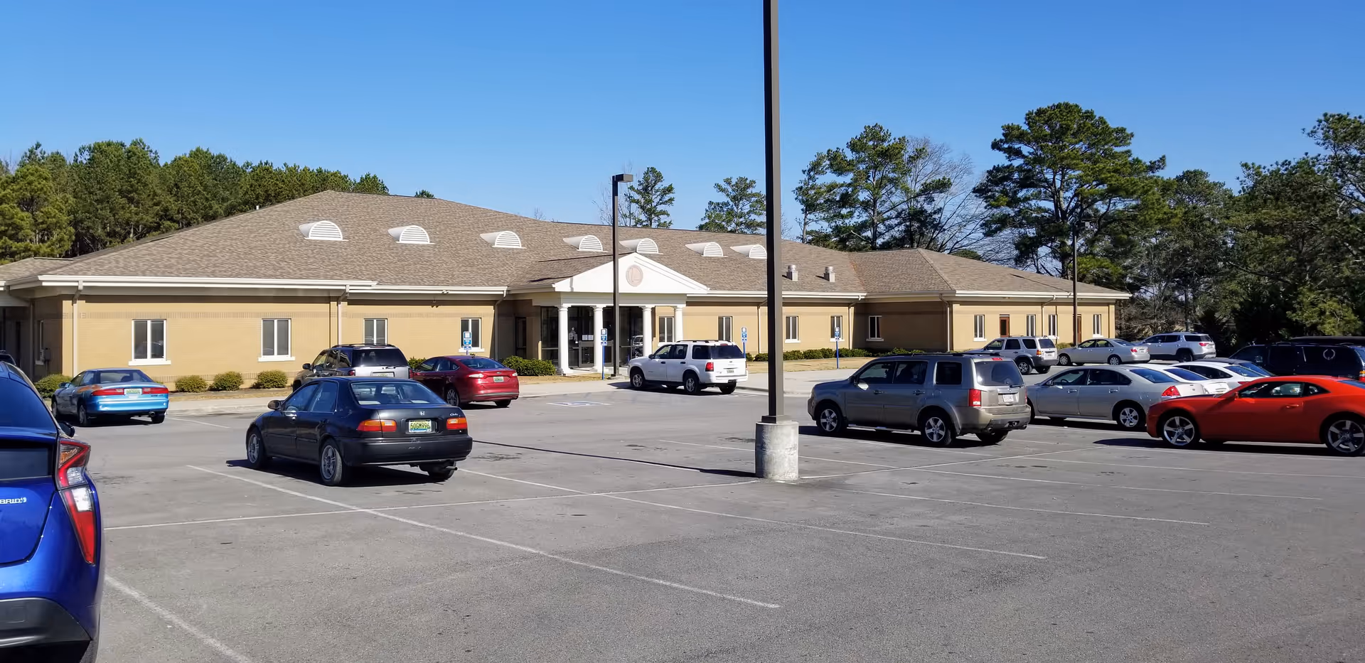 Exterior view of a single-story facility with a parking lot in front.