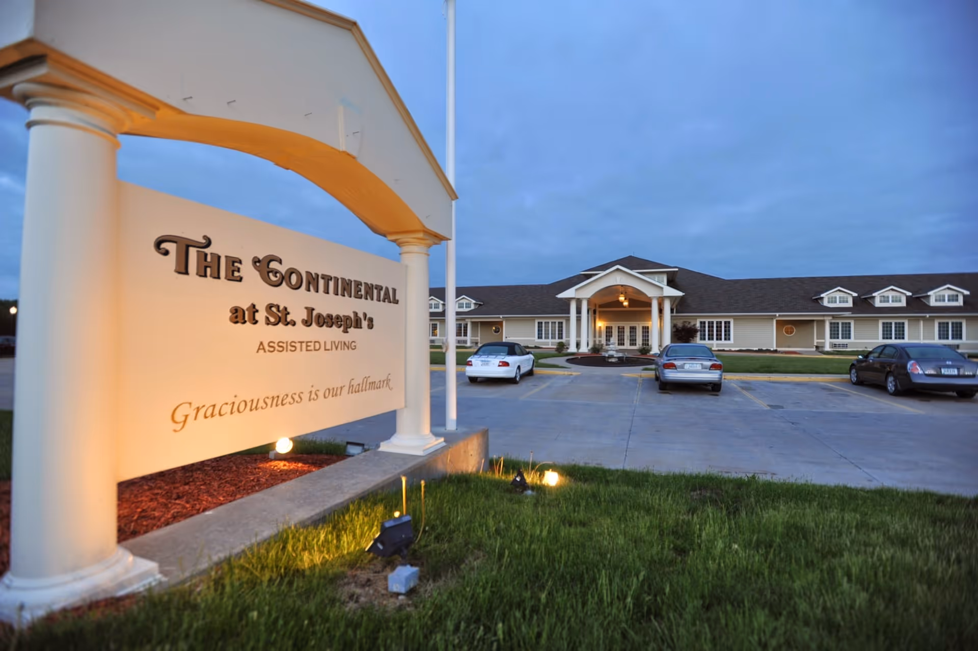 Exterior front view of The Continental at St. Joseph's Assisted Living with entrance sign and parking.