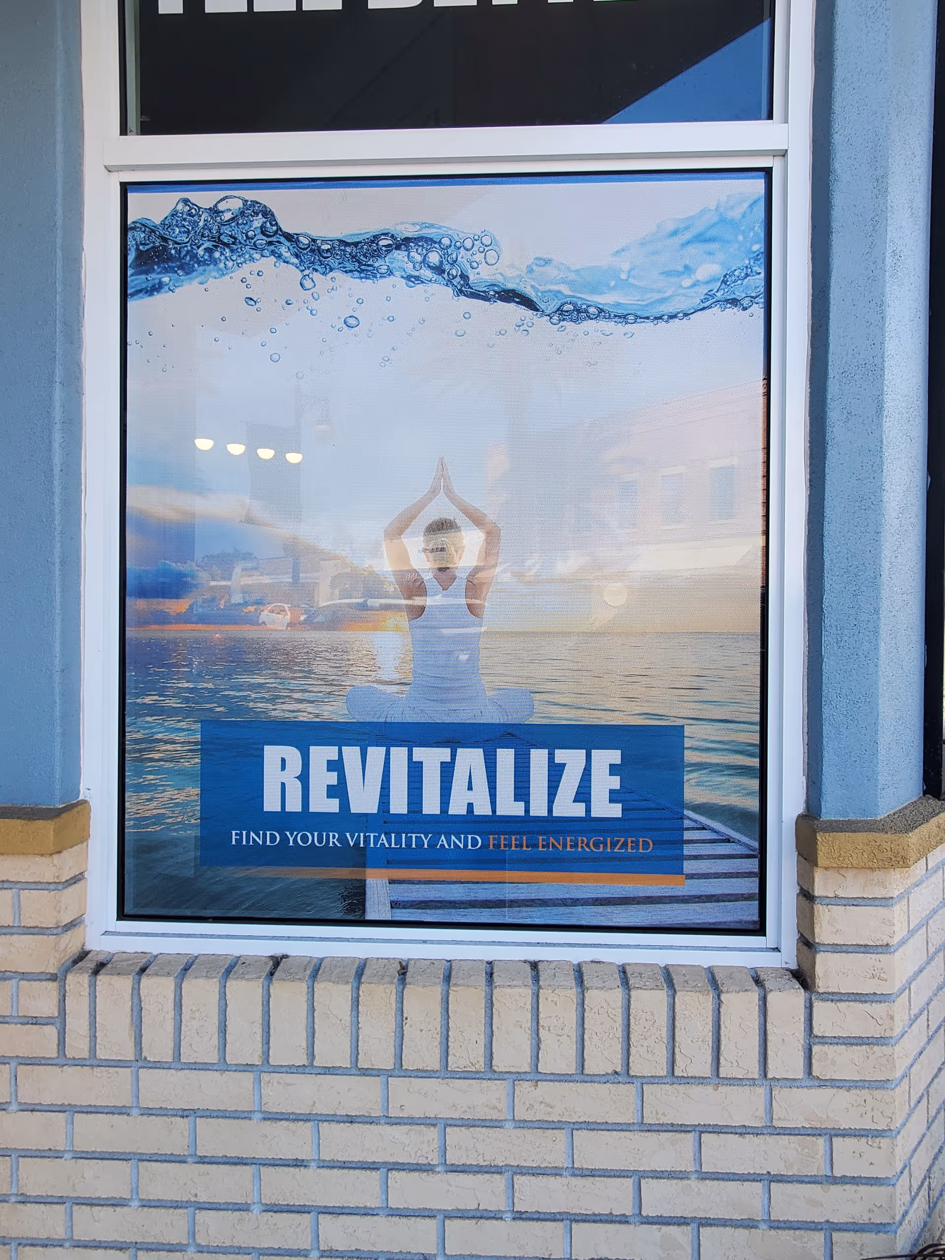 Storefront window ad featuring a yoga pose with waves and Revitalize banner
