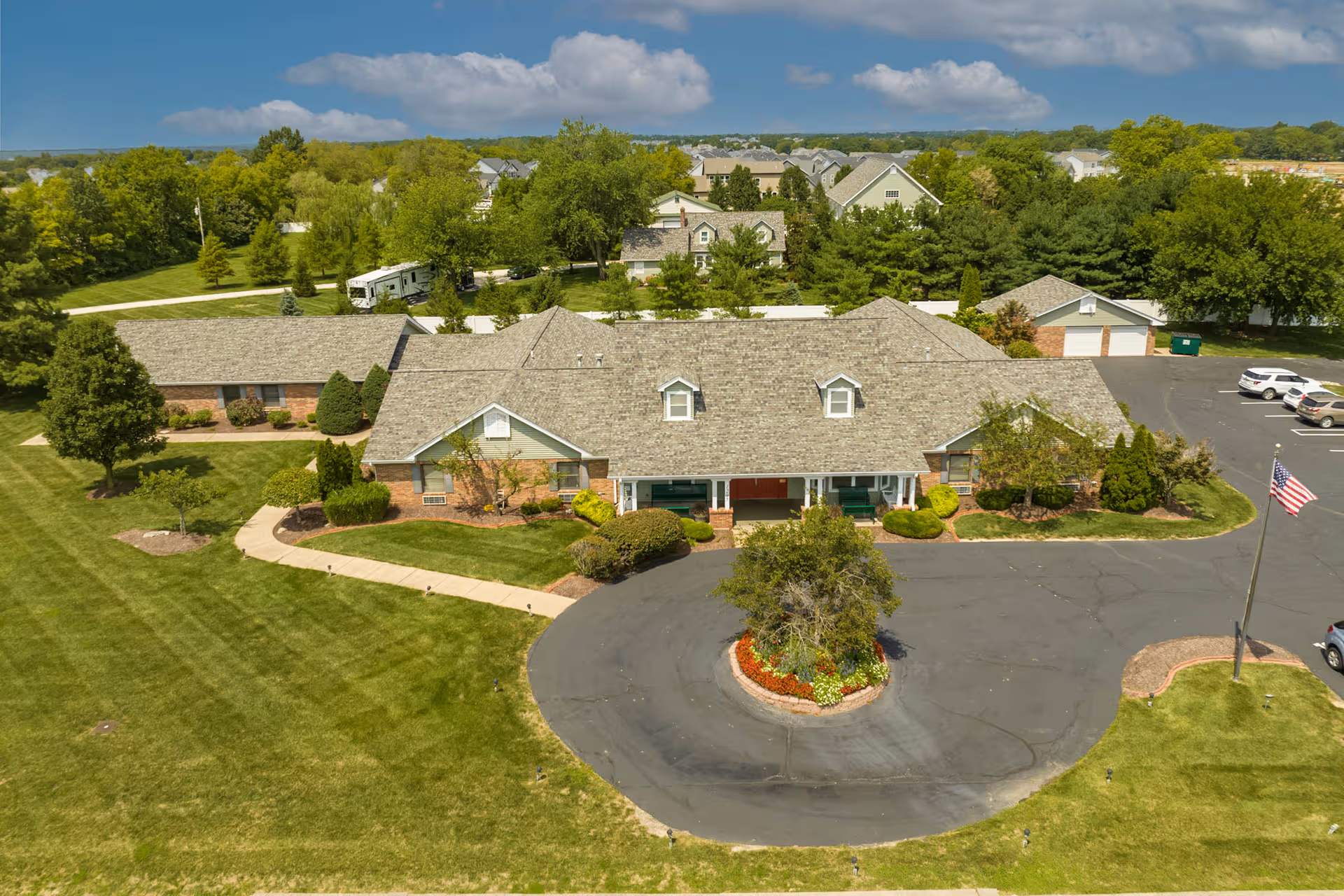 A large, single-story senior living facility with a circular driveway and manicured grounds.