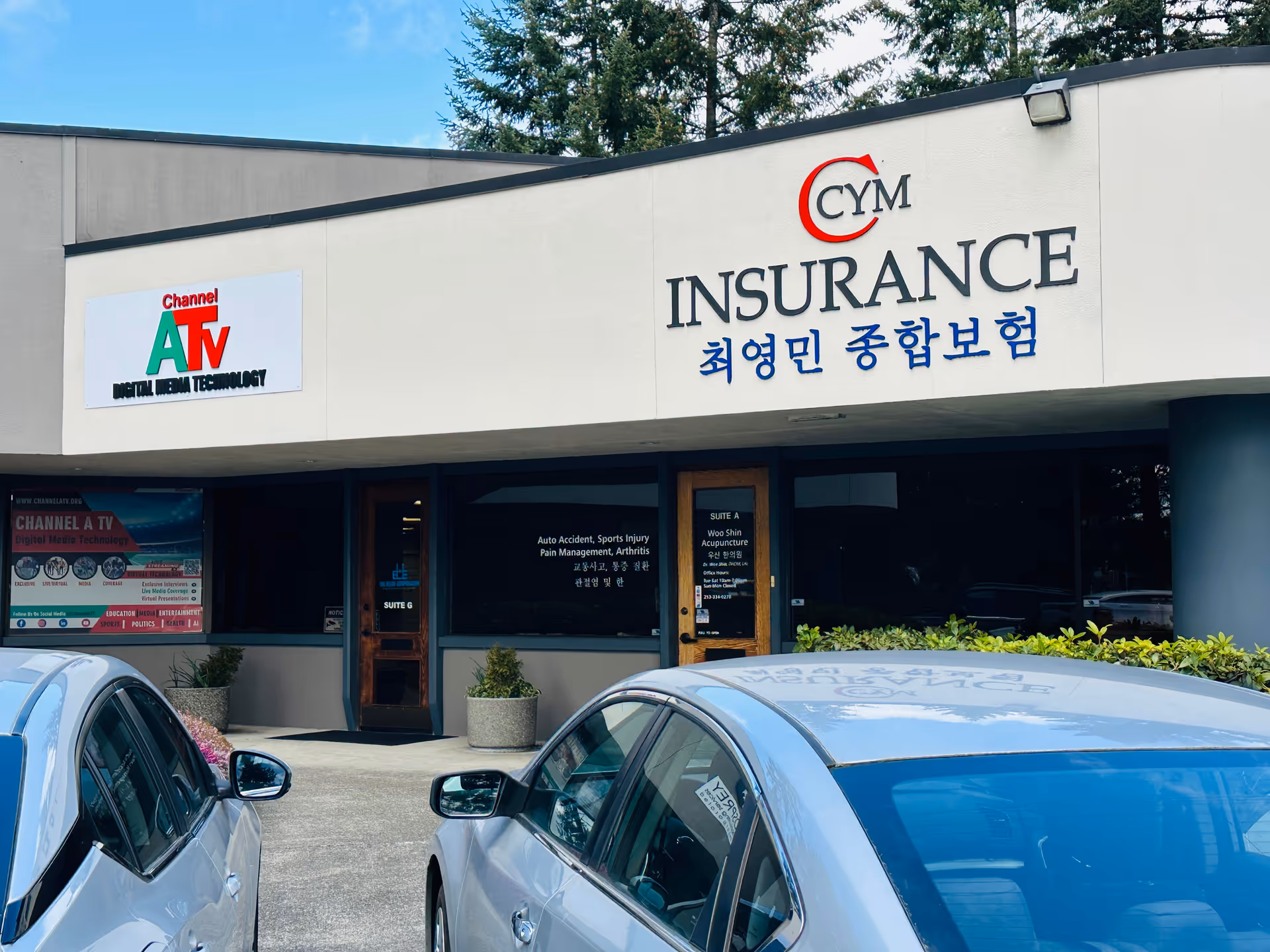 Front view of a commercial insurance office with CYM Insurance signage and parked cars.