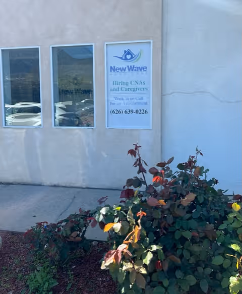 Exterior of New Wave Home Care in Pasadena, showing windows, a sign, and rose bushes.