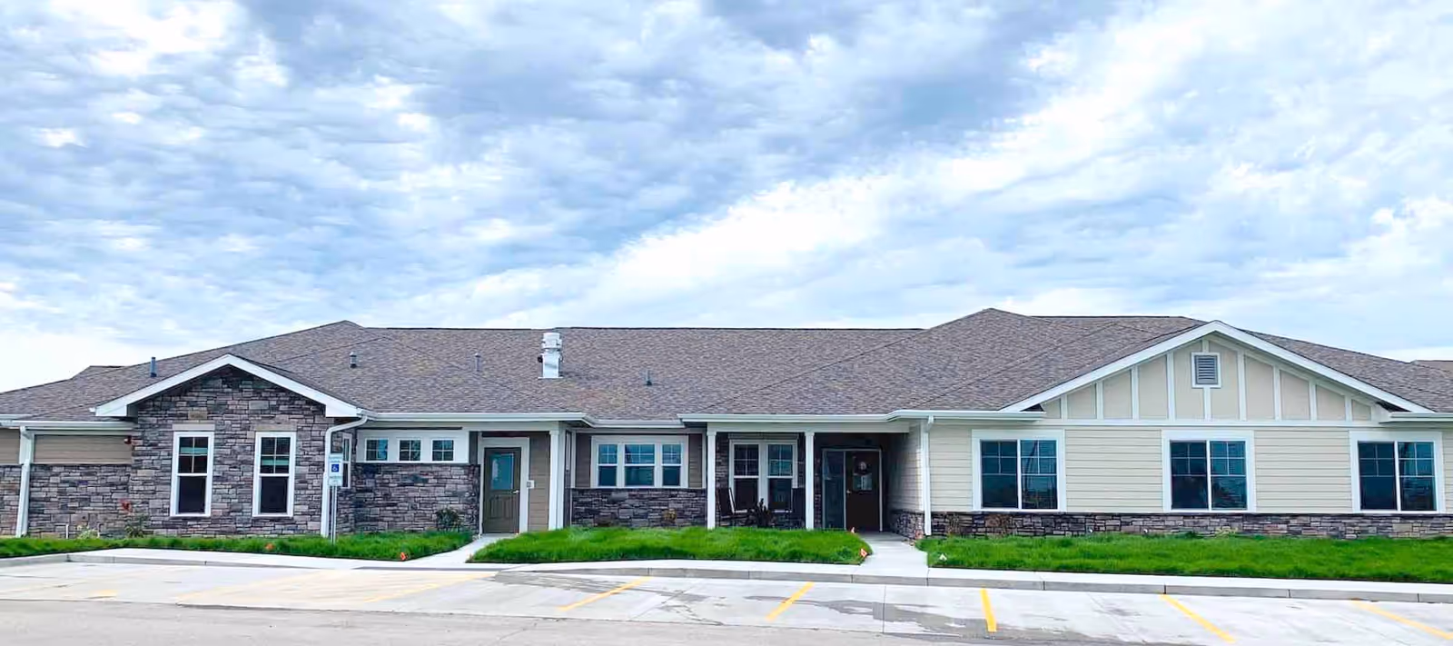 Front view of a single-story senior living facility with stone accents and a parking lot.