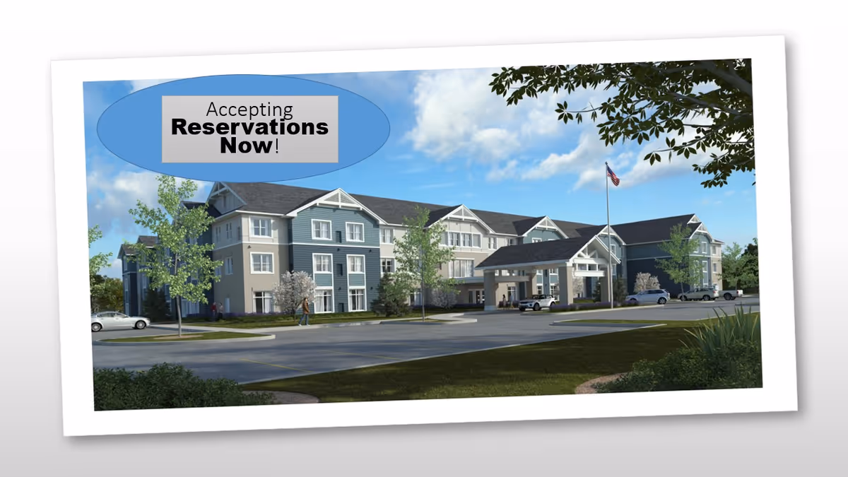 Exterior front view of a three-story senior living building with a covered entrance, landscaped grounds, parked cars, and an 'Accepting Reservations Now!' banner.