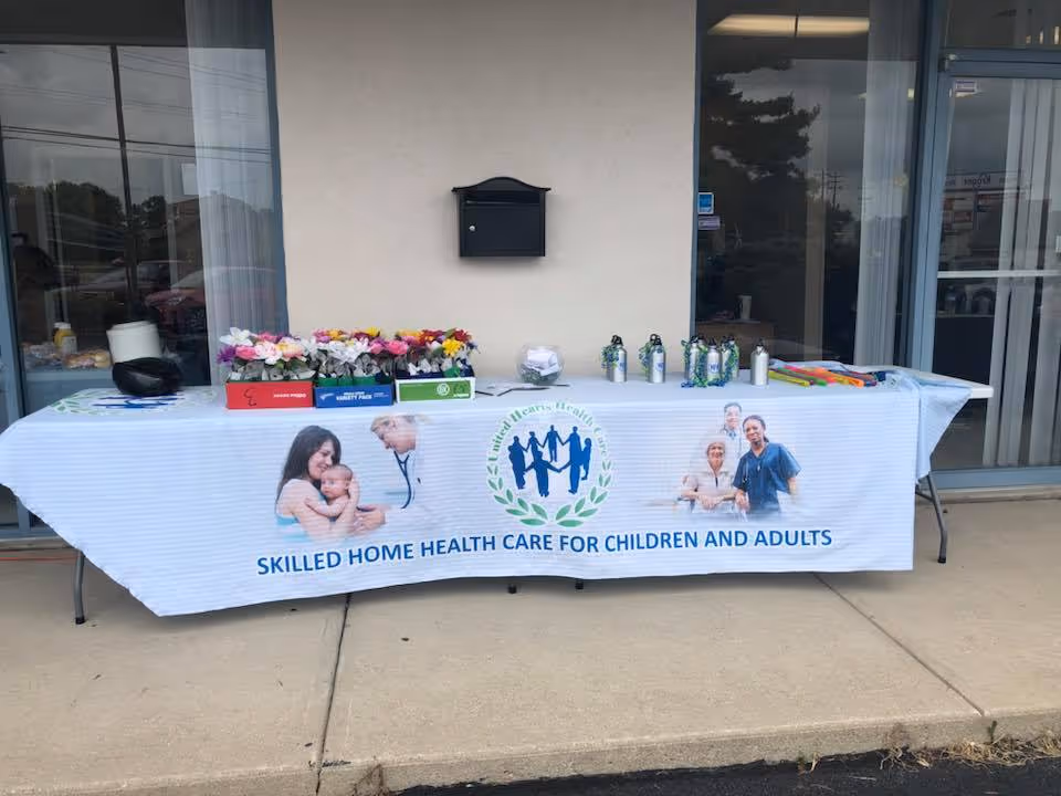 Outdoor display table with flowers and promotional materials outside United Hearts Health Care entrance.