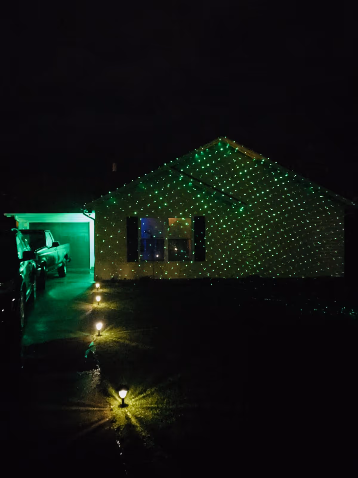 Night exterior of a senior living home illuminated by green string lights.