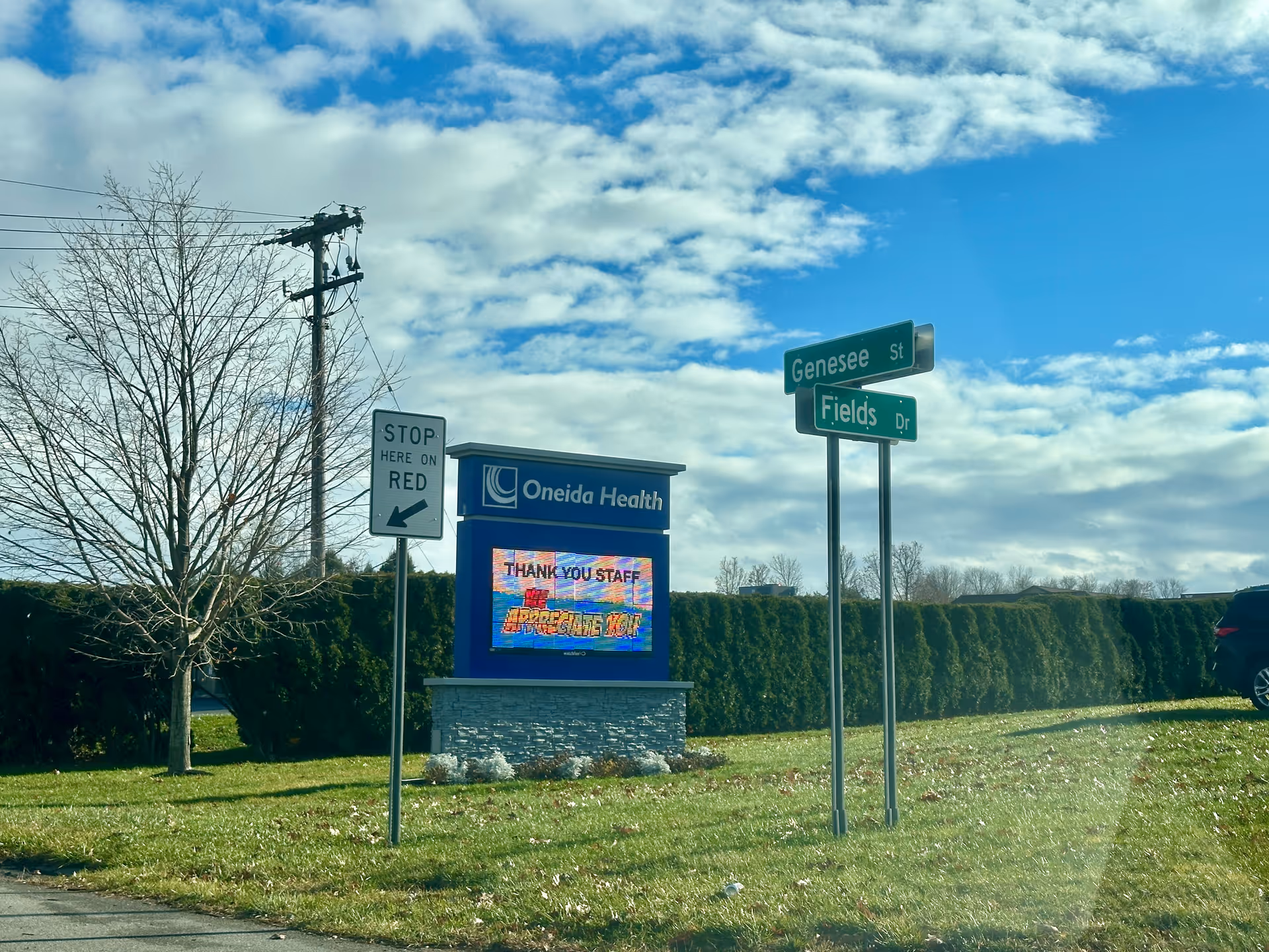 Exterior view of Oneida Health Rehabilitation and Extended Care sign with street signs and blue sky.