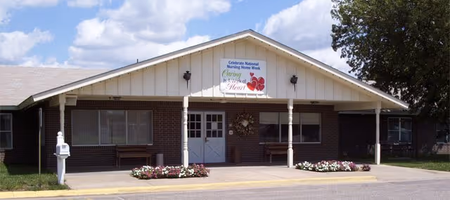 Front view of The Shepherd's House of Love facility with a covered entrance and flowers.