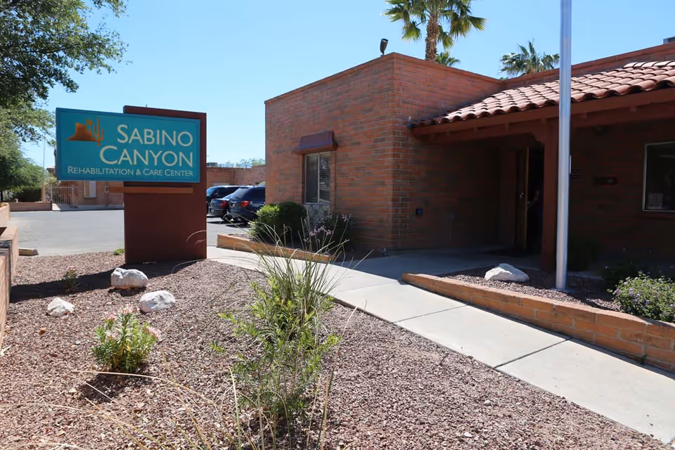 Exterior view of Sabino Canyon Rehabilitation & Care Center entrance with sign and brick building.